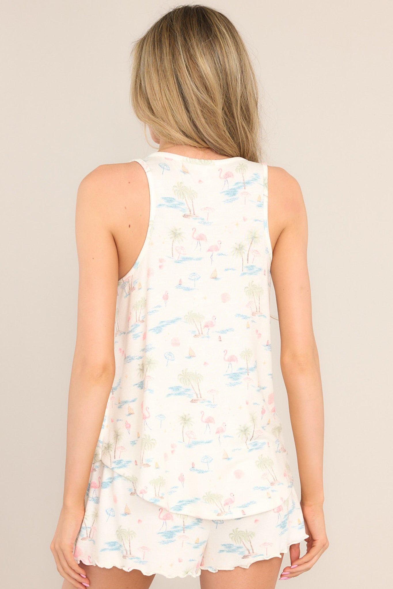 Back view of this top that features a v-neckline, a tank top design, a soft & lightweight material, a tropical pattern, and a scooped hemline.