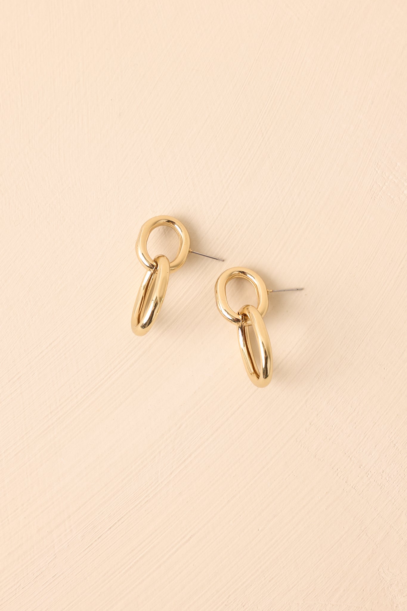 Side view of the interlocking gold link earrings showing their dimensional shape and post backings.