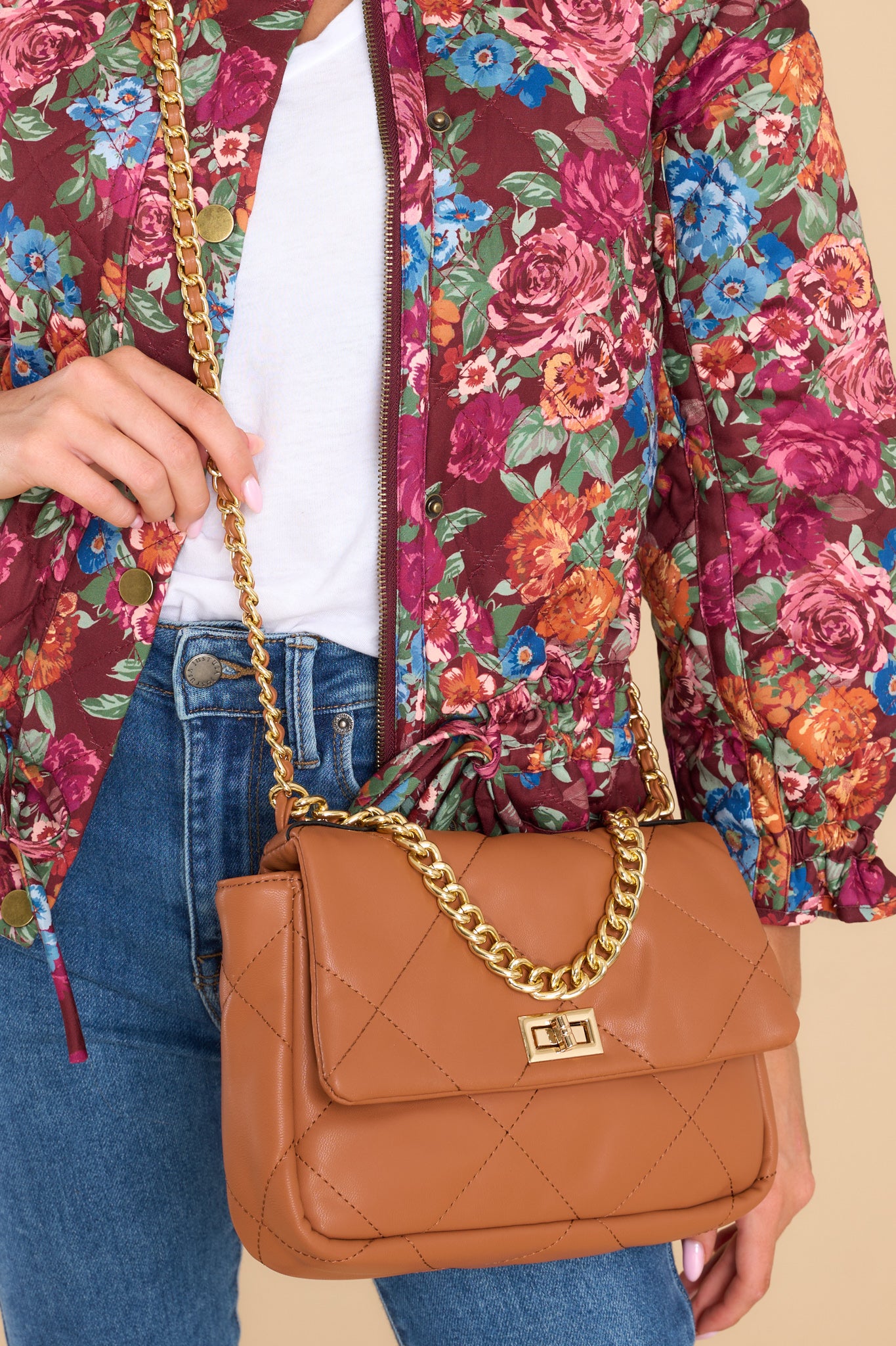 Front view of brown bag with a zipper pocket inside, one short chain link strap, and an attached crossbody strap.