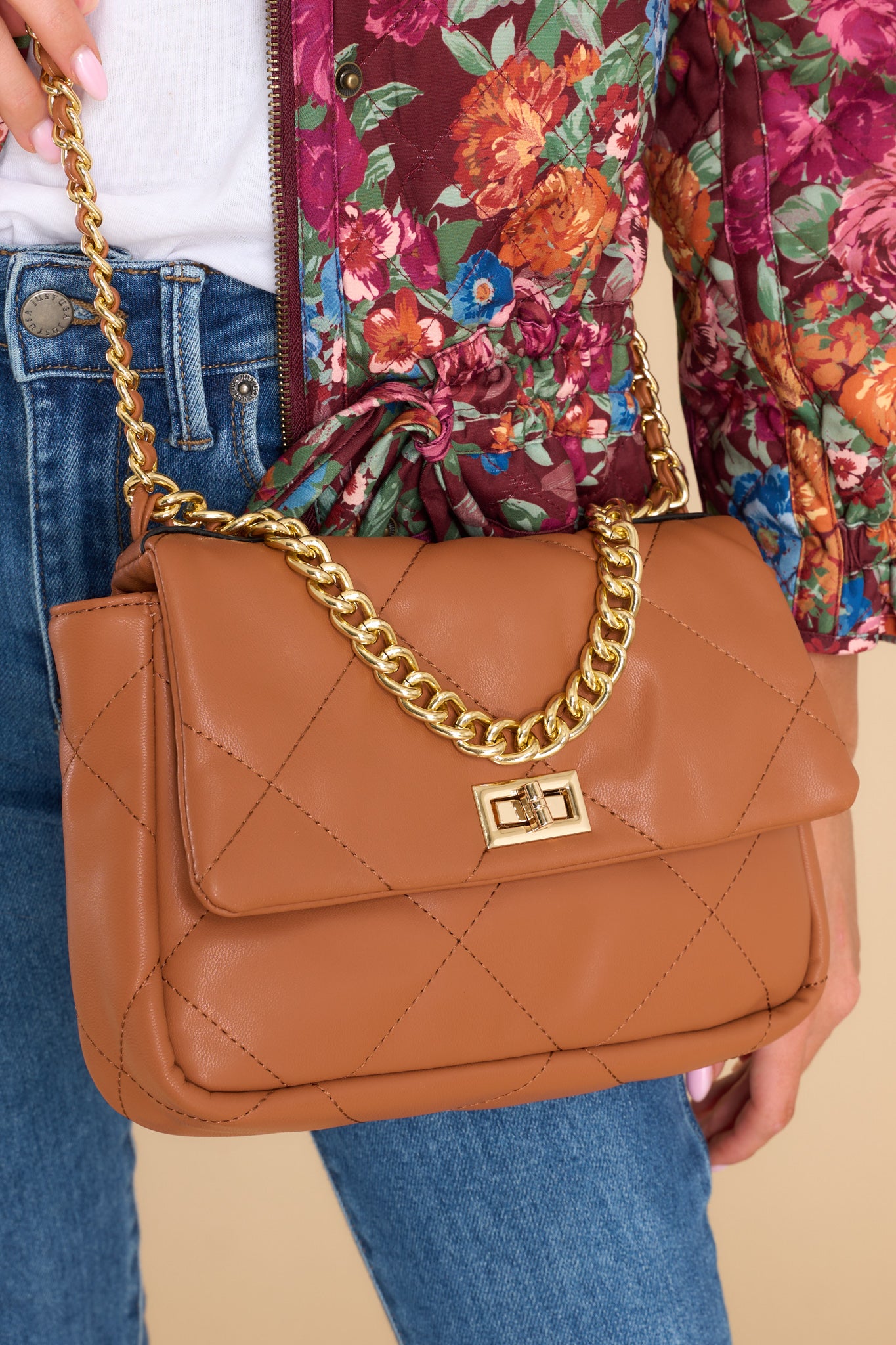 Front view of bag featuring a faux leather body, gold-colored hardware, a twist lock closure, and outside pocket with a snap button closure.