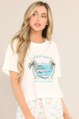 Angled front view of this tee that features a crew neckline, dropped shoulders, a tropical graphic, a slightly cropped length, a split hemline, and short sleeves.