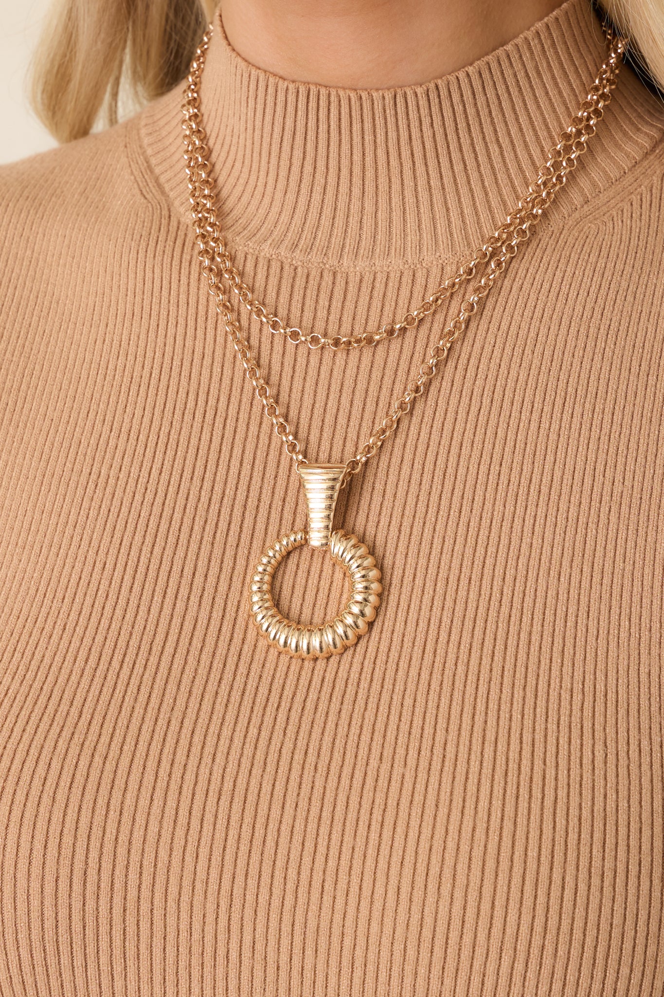 Detailed close-up of gold necklace highlighting double-layer chain links, lobster clasp closure, and pendant detail.