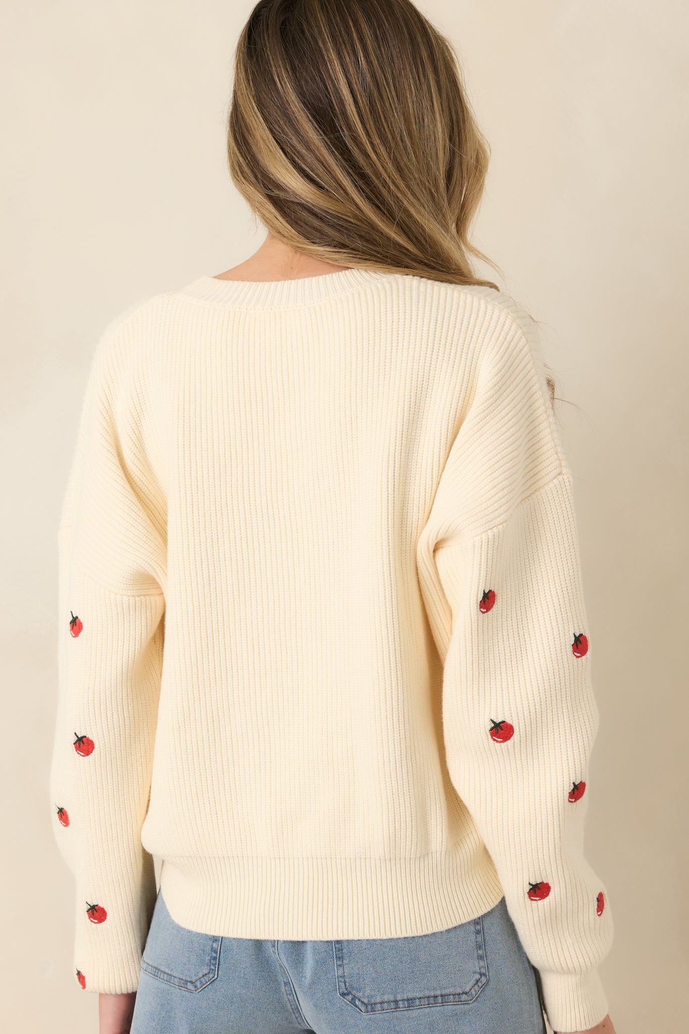 Rear view of the ivory ribbed sweater showing allover tomato embroidery, long sleeves, and relaxed fit.