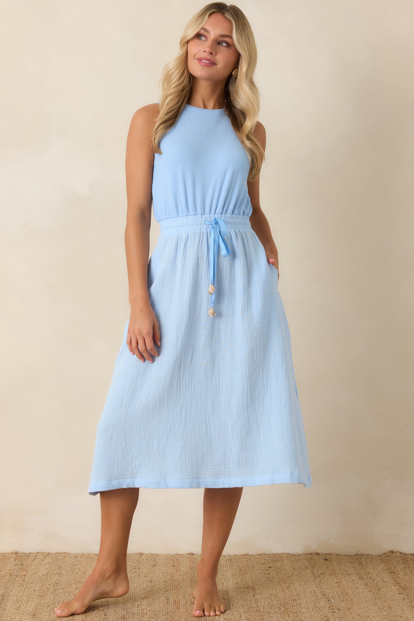 Lightweight sleeveless midi dress with round neckline and adjustable waist tie creating a flattering shape.