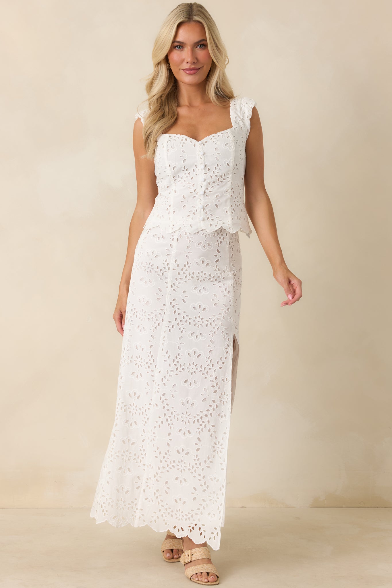 Cotton eyelet top in white featuring a scalloped hem, front covered button accents, and a structured fitted silhouette.