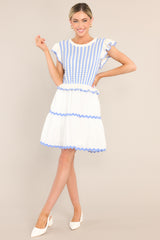 Full body view of this dress that features a scalloped crew neckline, a striped knitted bodice, a ruffled waistline, functional pockets, scalloped detailing, a scalloped hemline, and ruffled sleeves.