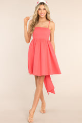 This coral colored dress features a square neckline, skinny adjustable shoulder straps, a back zipper with a wrap around self-tie bow, waist pockets, and flowy short skirt. 
