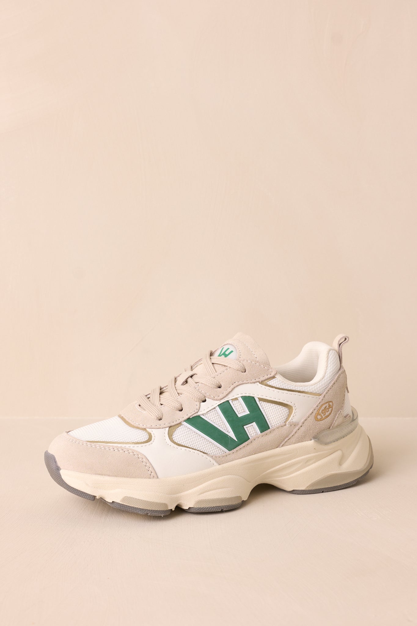 A dynamic view of the sneakers, highlighting the rounded toe, functional tan laces, and sleek mix of green, white, and tan.