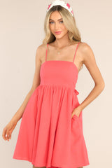 Front view of this dress that features a square neckline, skinny adjustable shoulder straps, a back zipper with a wrap around self-tie bow, waist pockets, and flowy short skirt.