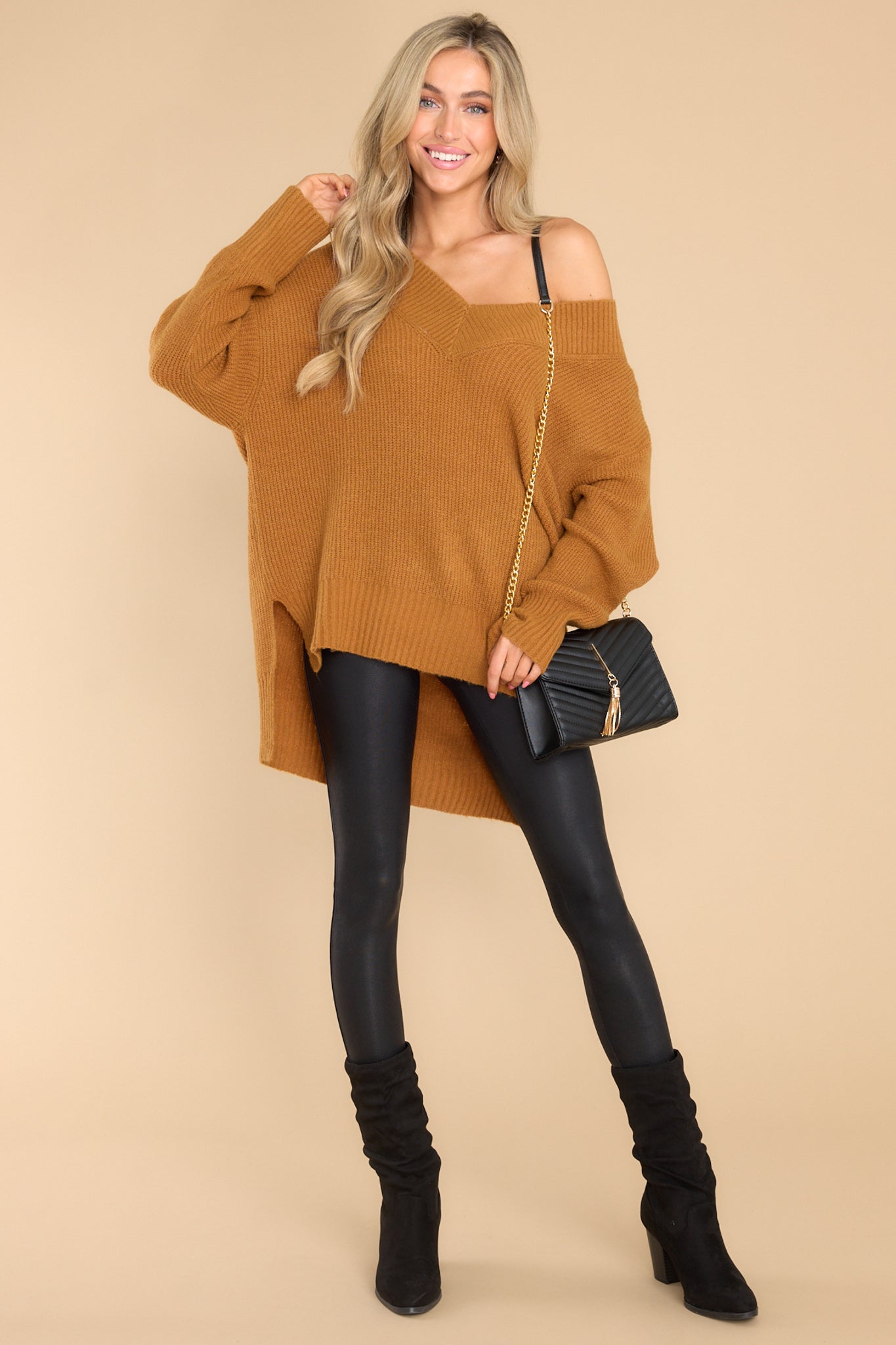 Full body view of this sweater that features a wide v-neckline, long sleeves with ribbed cuffs, a bottom hem that is longer in the back and has small slits up both sides, and a super soft feel throughout.