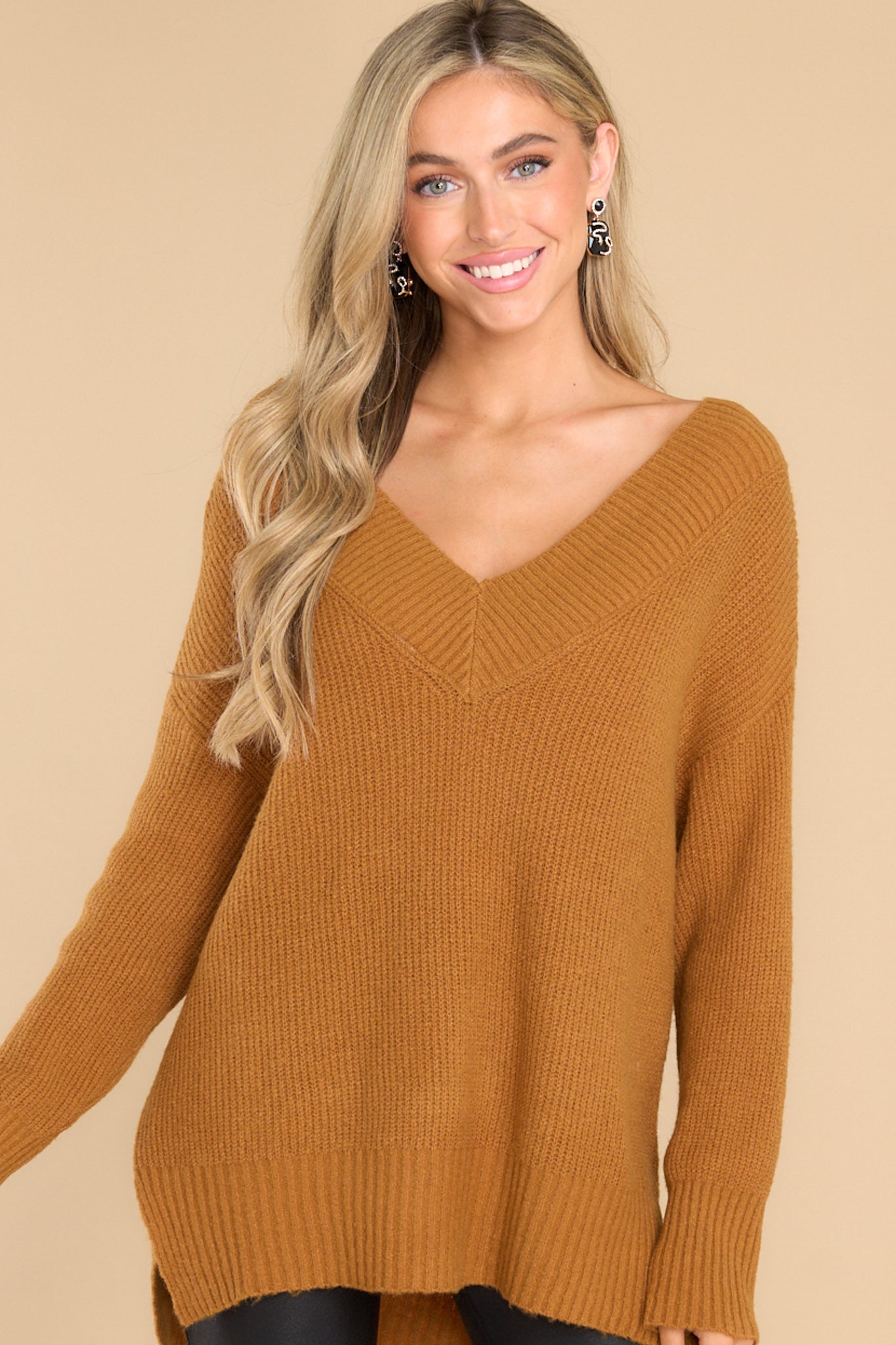 Front view of this sweater that features a wide v-neckline, long sleeves with ribbed cuffs, a bottom hem that is longer in the back and has small slits up both sides, and a super soft feel throughout.