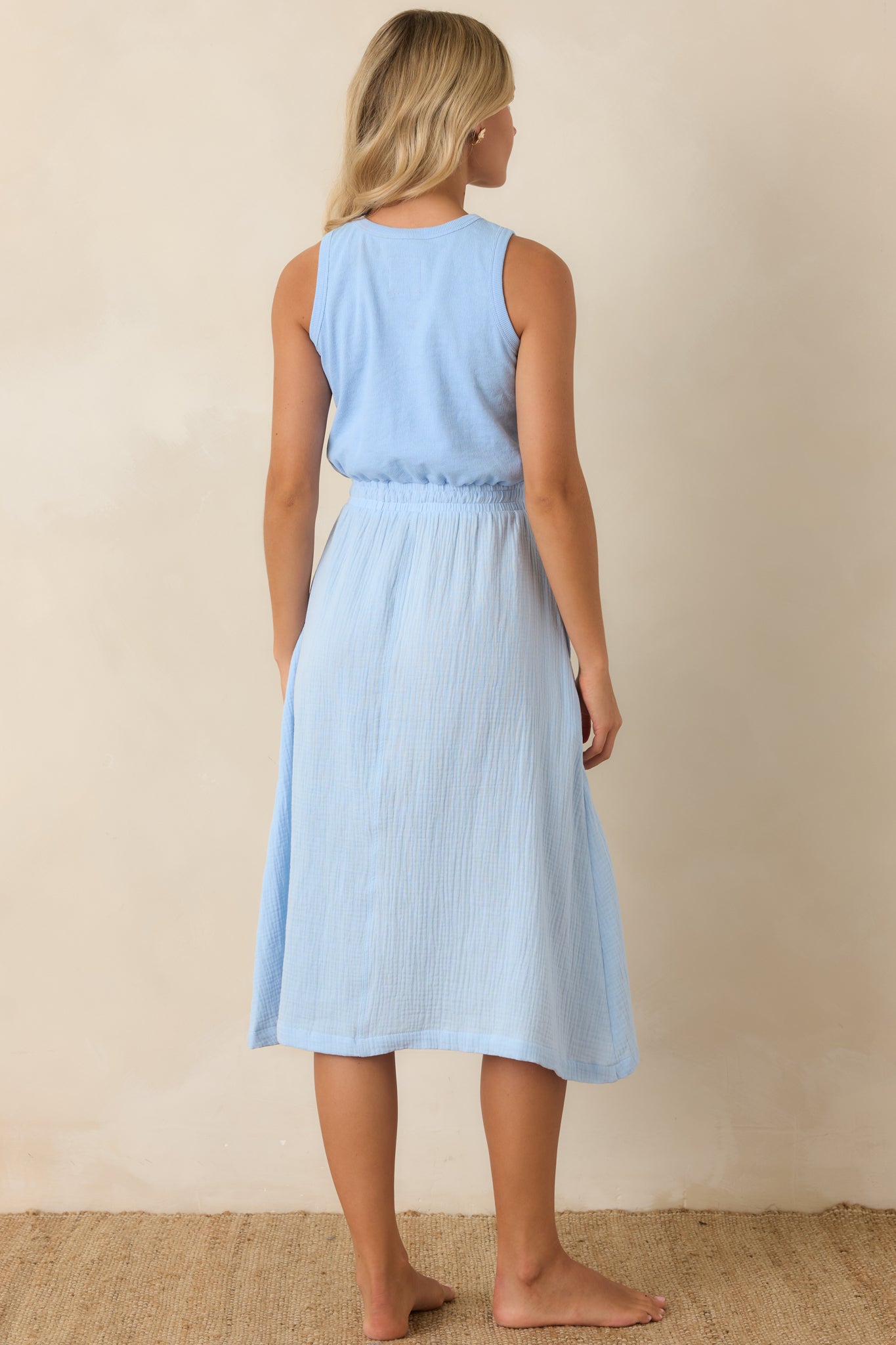 Rear view of sleeveless textured cotton midi dress with relaxed fit and softly gathered waistline.