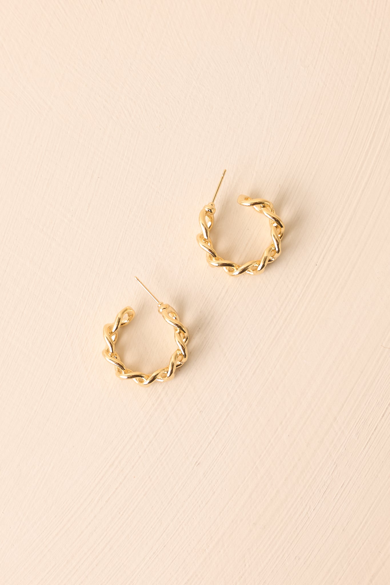A cropped view of the gold earrings with a chain link design in an open hoop style.