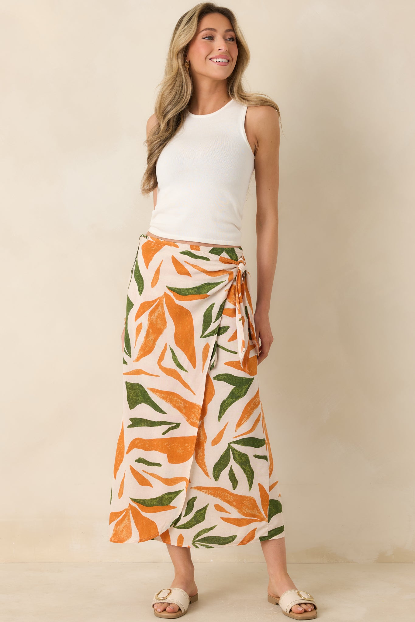 Full body view of this tropical print midi skirt that features a high waisted design, an elastic waist insert, self-tie wrap features, an orange & green tropical print, and a lightweight fabric.