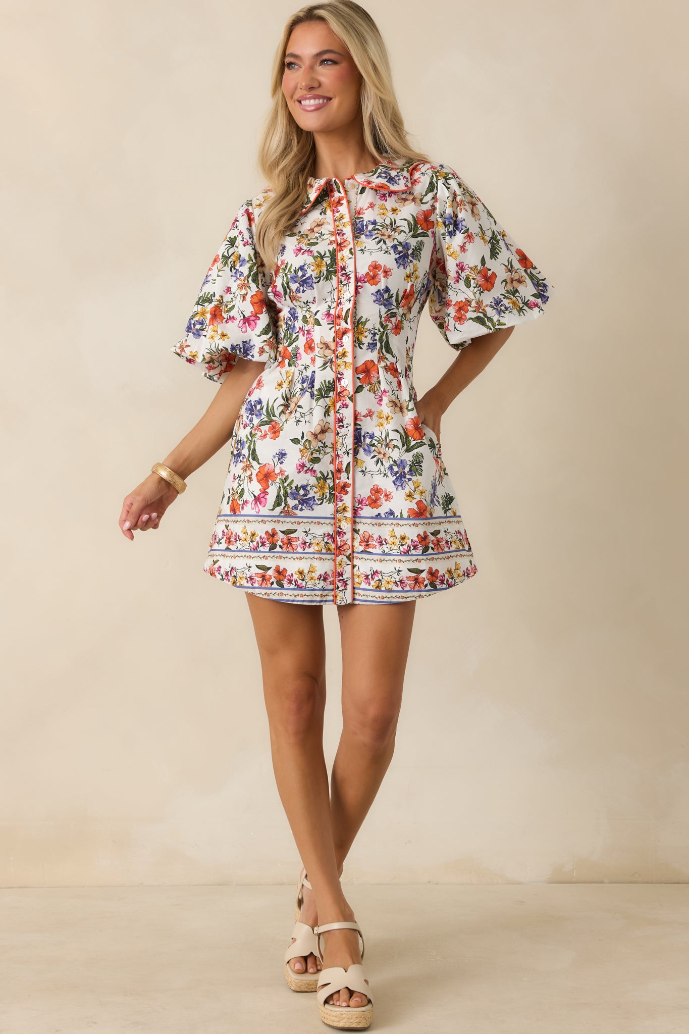 Floral mini dress in ivory tones with bright multicolor blooms, soft bubble sleeves, and a breezy relaxed silhouette with subtle volume.