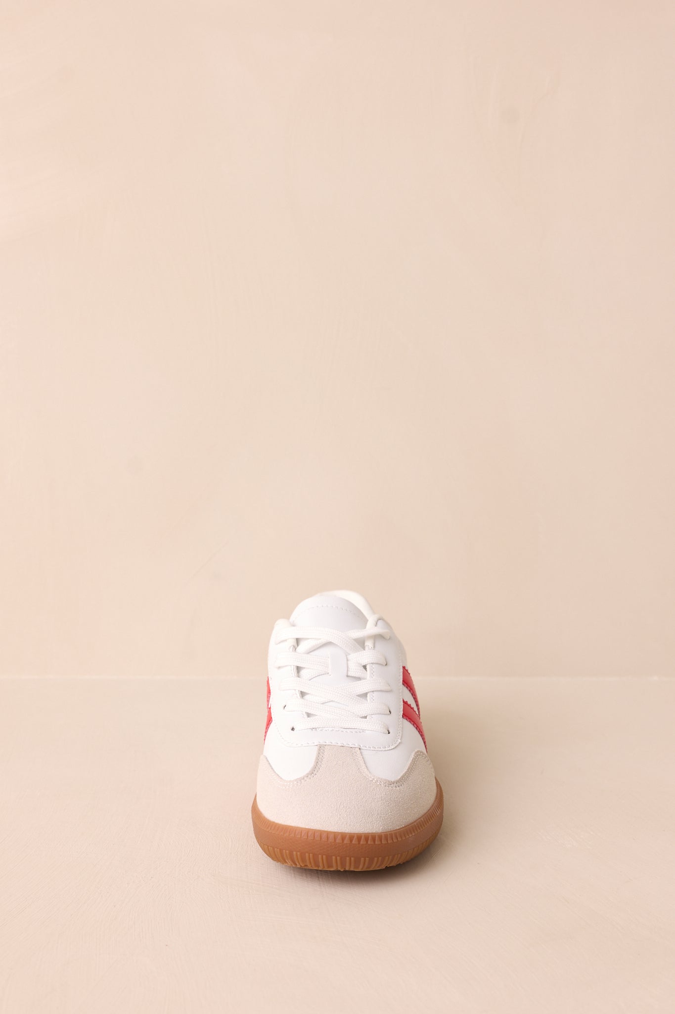 A white faux leather sneaker with a round toe, white laces, and a brown sole for a classic look.
