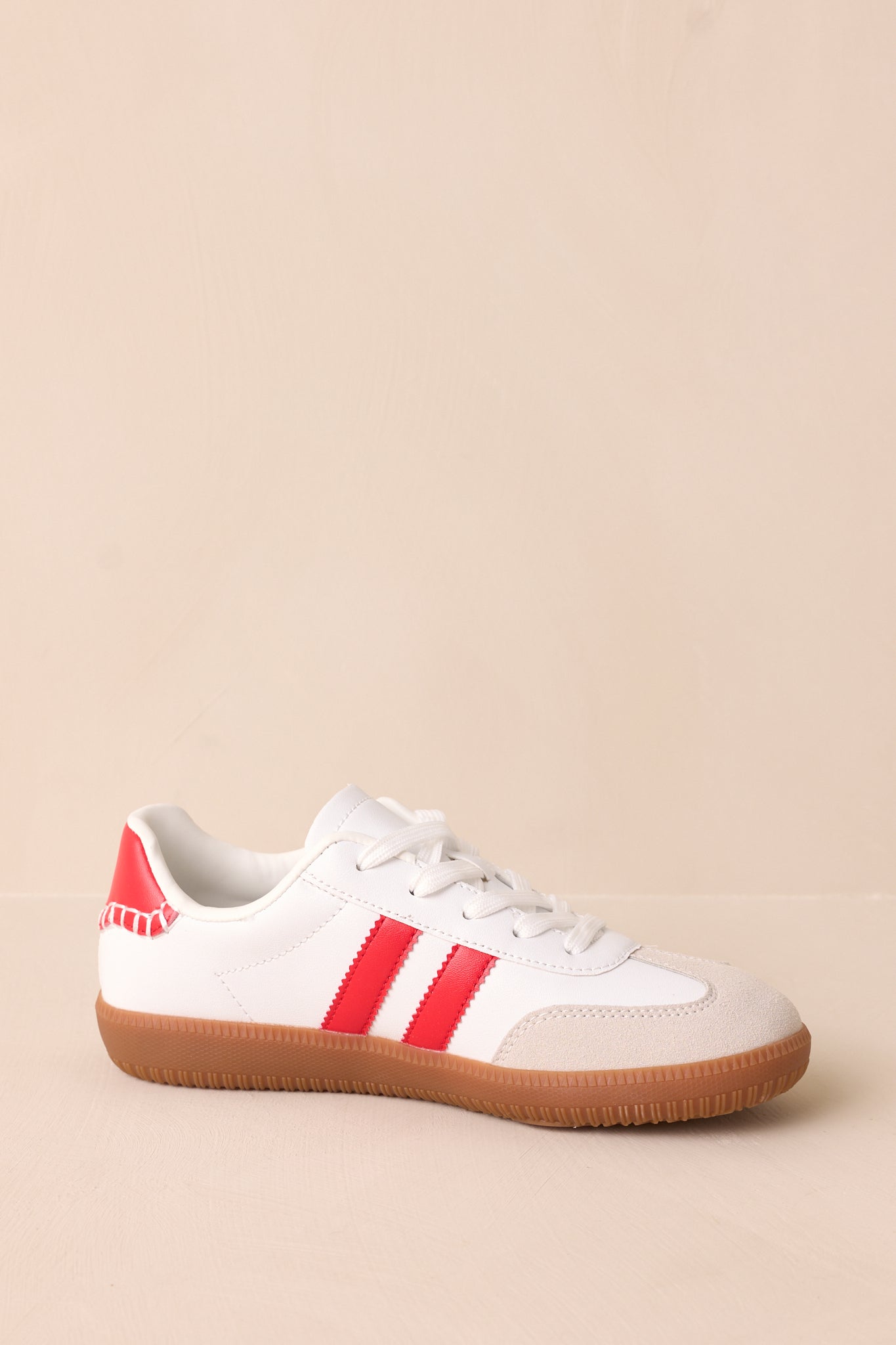 The sneaker features two red faux leather ricrac stripes on the side, adding a bold contrast against the white material.