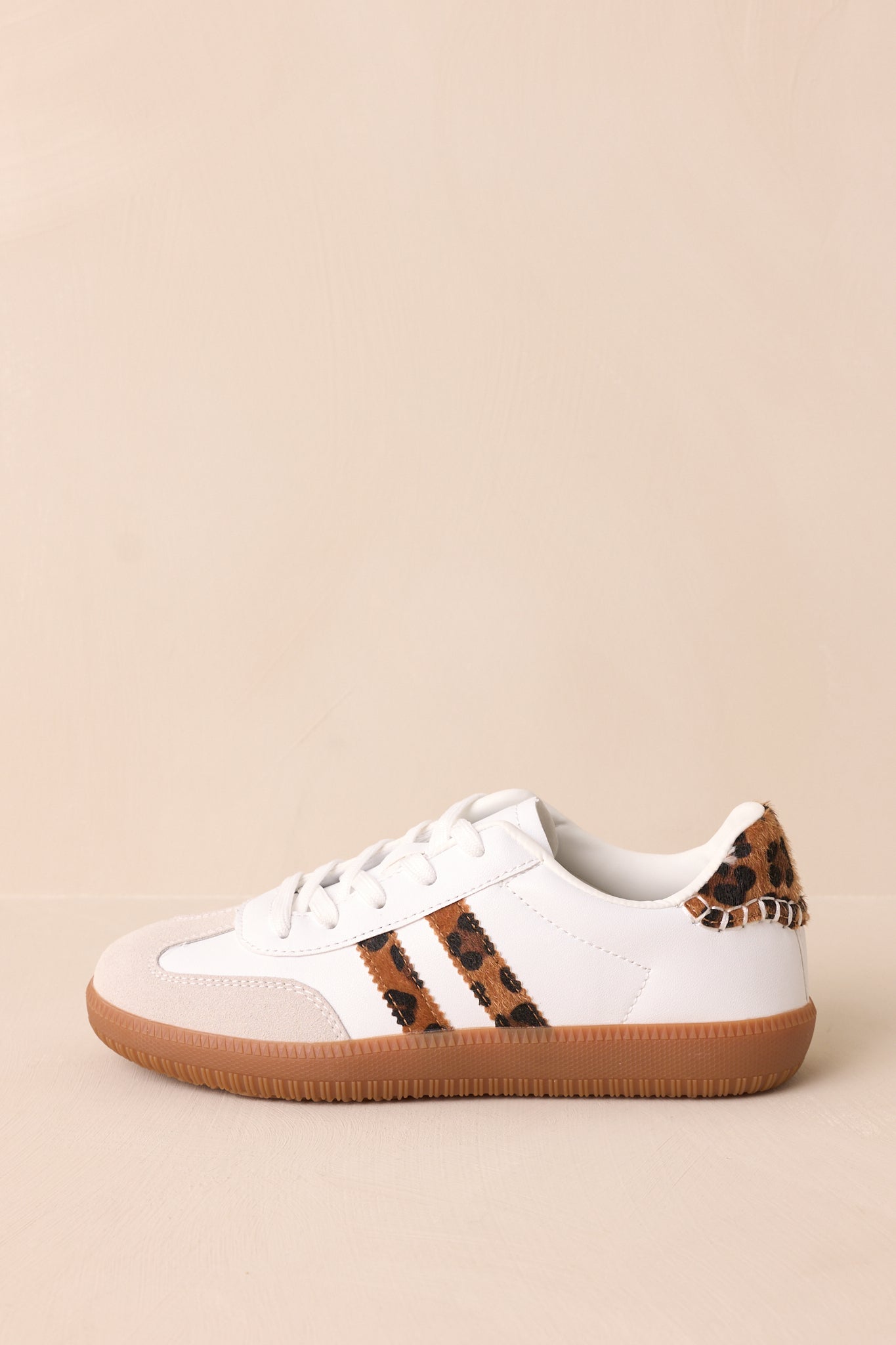 A side view of the white sneakers, showing off the round toe design, brown sole, and the bold leopard faux fur accents along the sides and ankle.