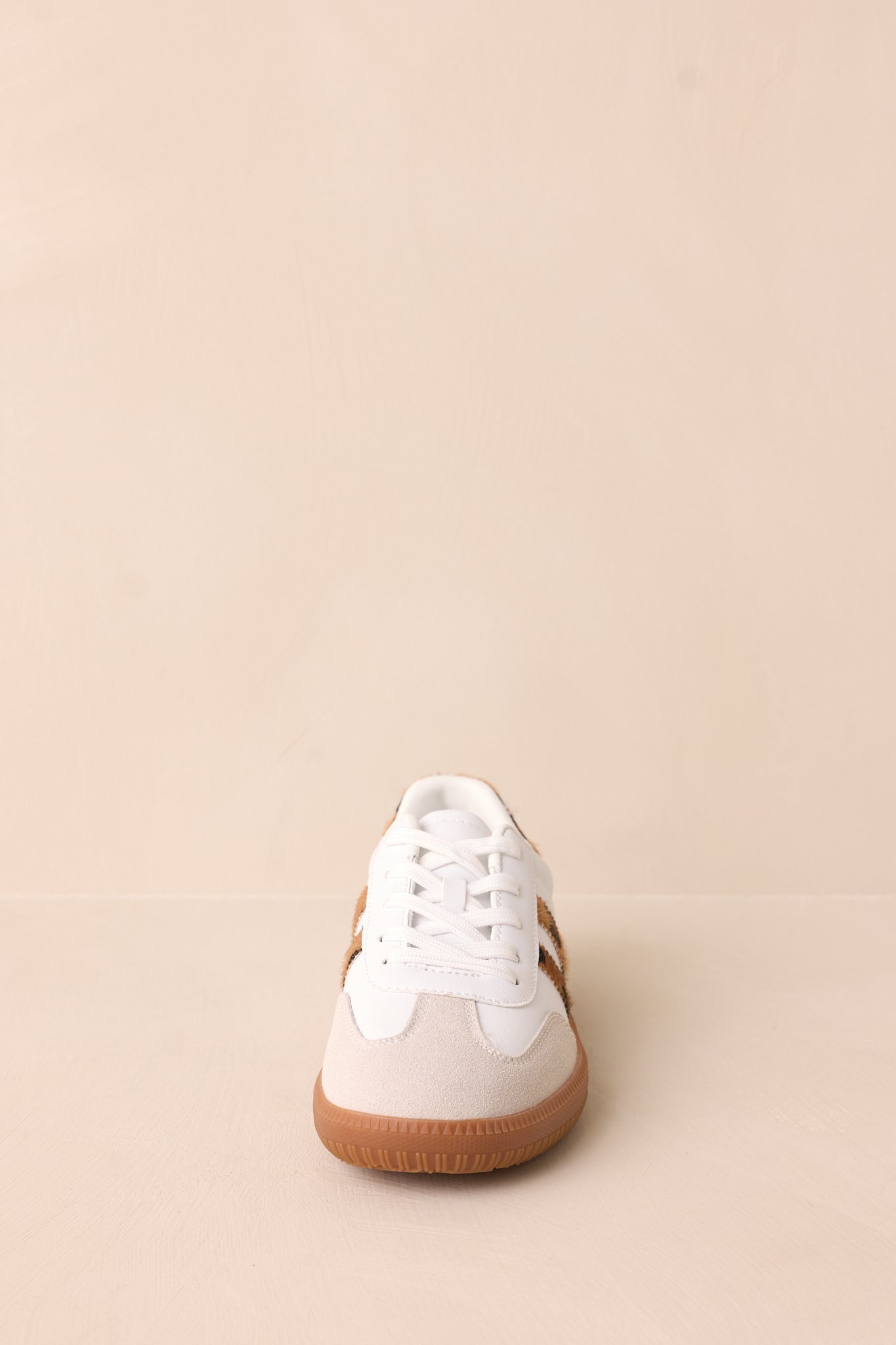 The sneakers are shown from another angle, showcasing the mix of white faux leather and leopard faux fur, with the round toe and lace-up design.