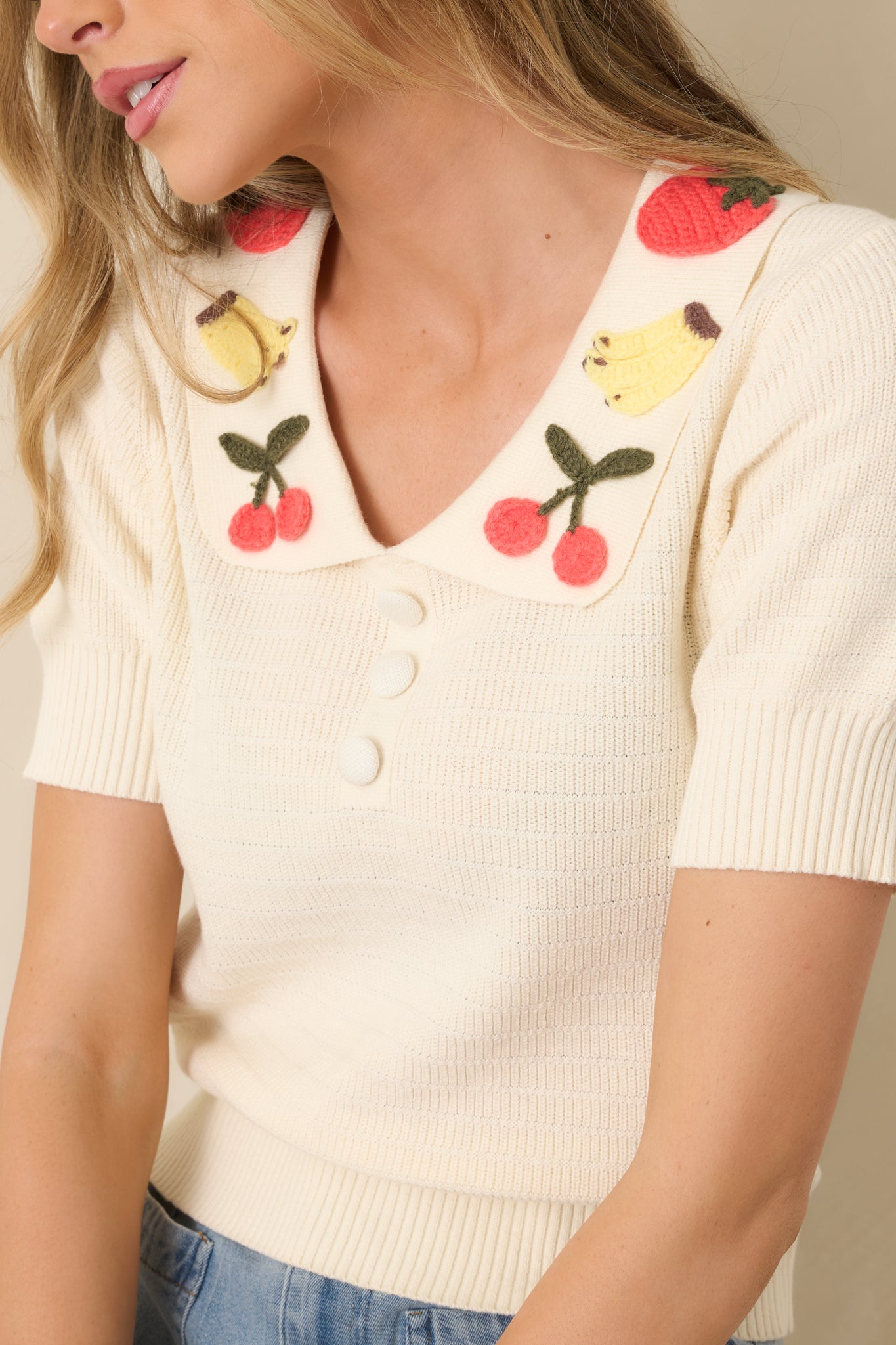 Soft ivory knit fabric at shoulder, showing ribbed texture and fine stitching.