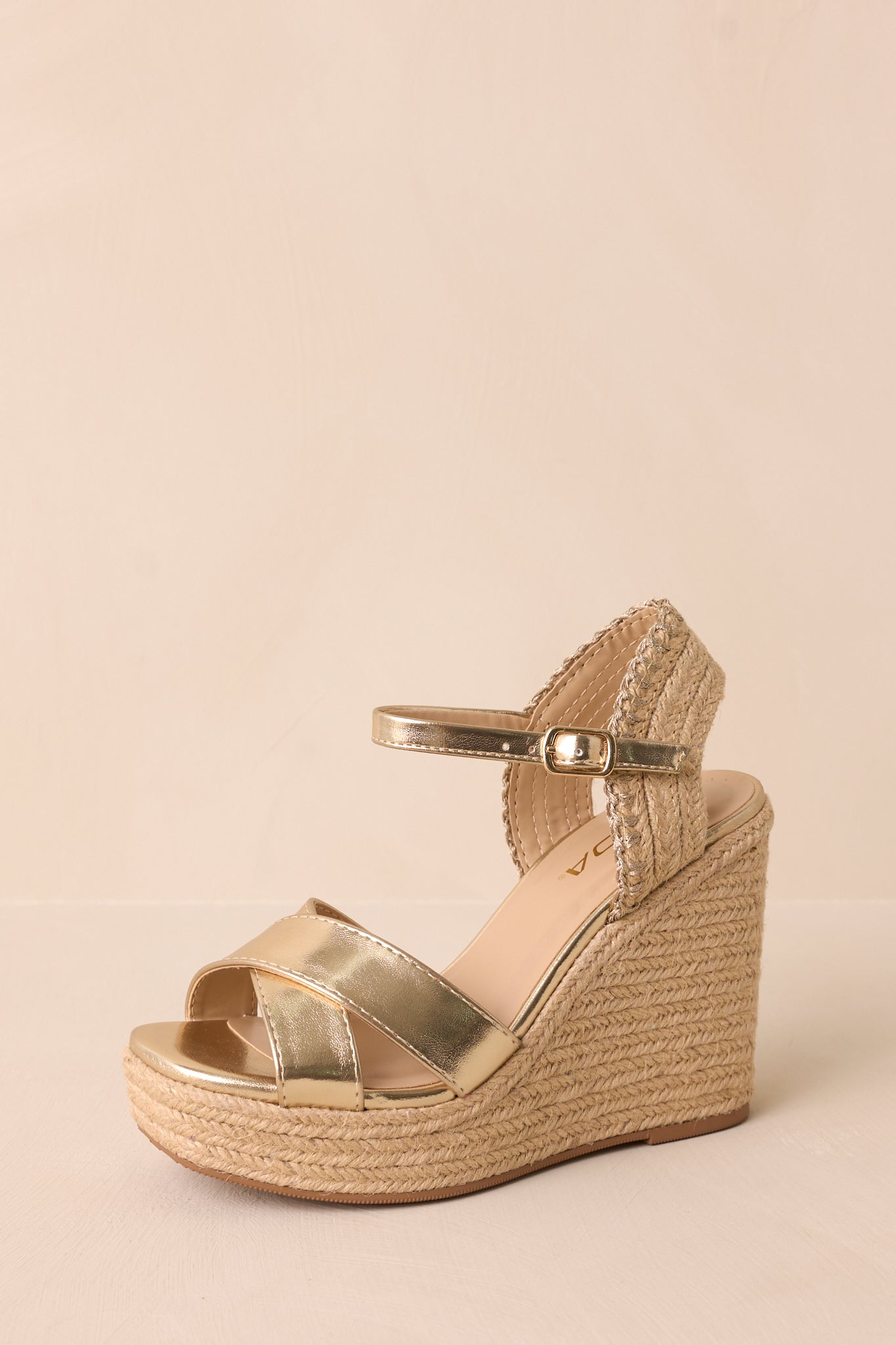 The front angled view of the sandals, emphasizing the rounded toe, cross strap design over the foot, and adjustable ankle strap, with the gold hardware and platform bottom.