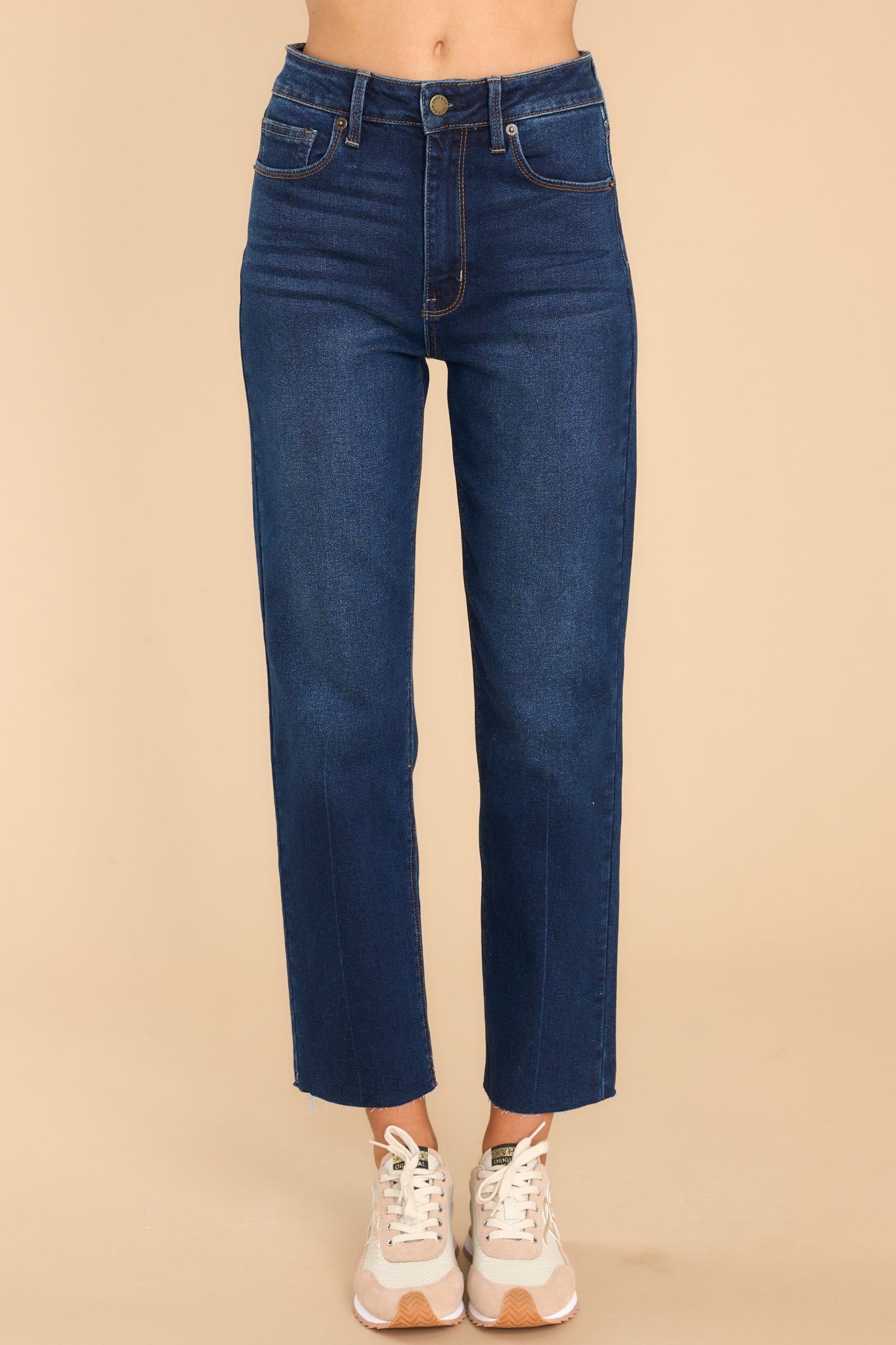 Front view of these jeans that feature a zipper down the front with one button closure, five functional pockets, a straight leg and a raw hem at the bottom.