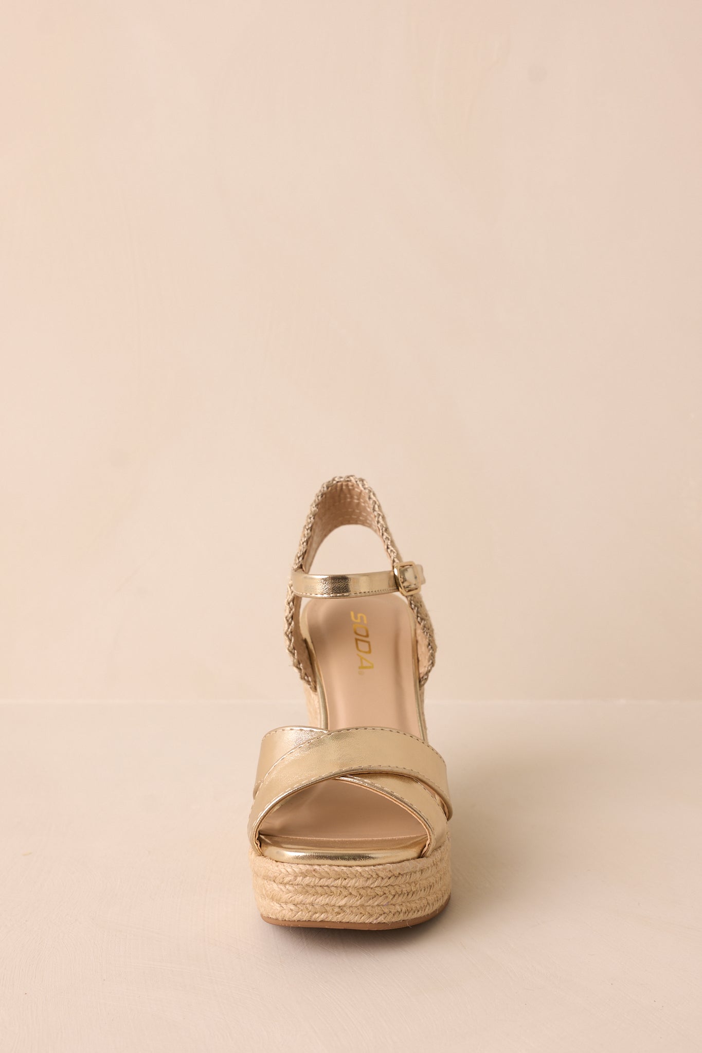 The front view of the sandals, emphasizing the rounded toe, cross strap design over the foot, and adjustable ankle strap, with the gold hardware and platform bottom.