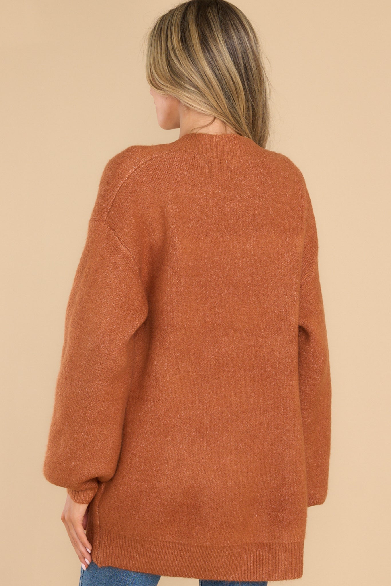 Back view of this cardigan that features a v-neckline, functional buttons down the front, two front pockets, ribbed cuffs, and slight balloon sleeves.