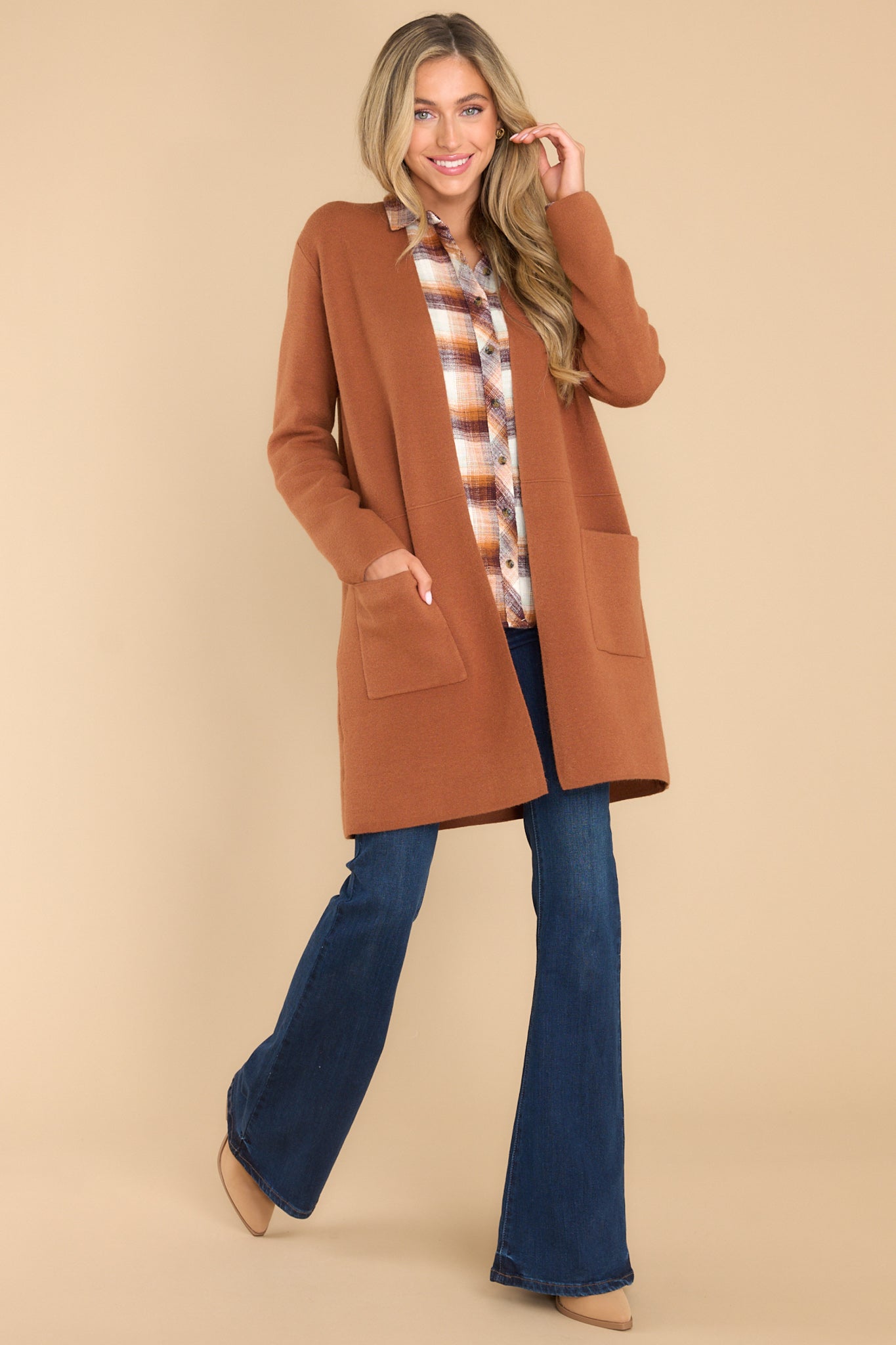 This brown cardigan features an open front design, two functional pockets, long sleeves, and a soft knit feel throughout.