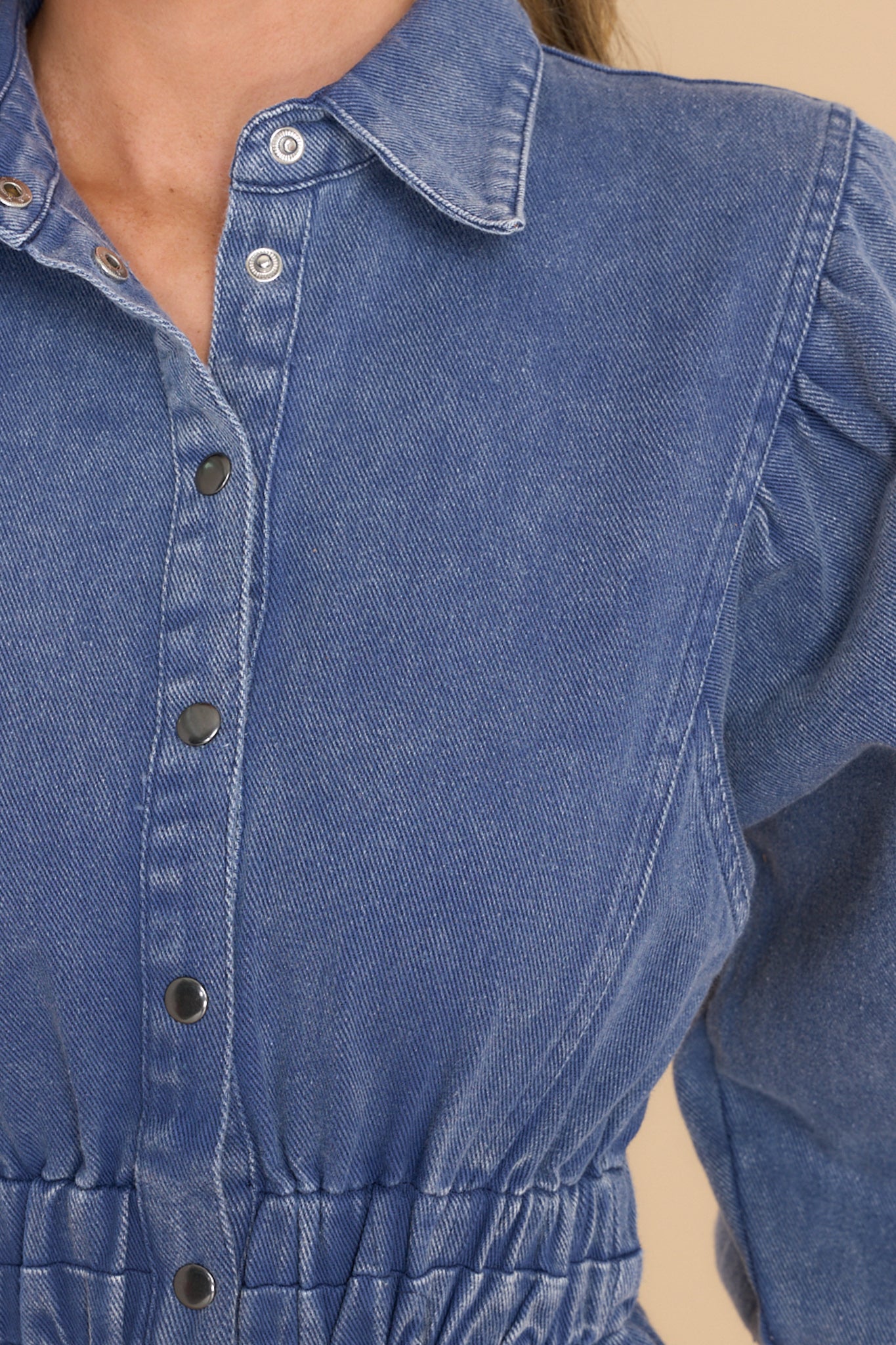 Close up view of this dress that features a collared neckline, functional silver buttons down the front, elbow-length sleeves with elastic cuffs, and an elastic waistband.
