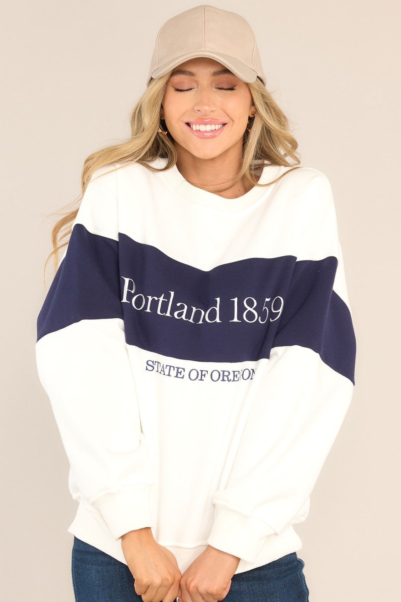 This white and navy sweatshirt features embroidered Portland text, a crew neckline, ribbed hems, and a cozy oversized fit.