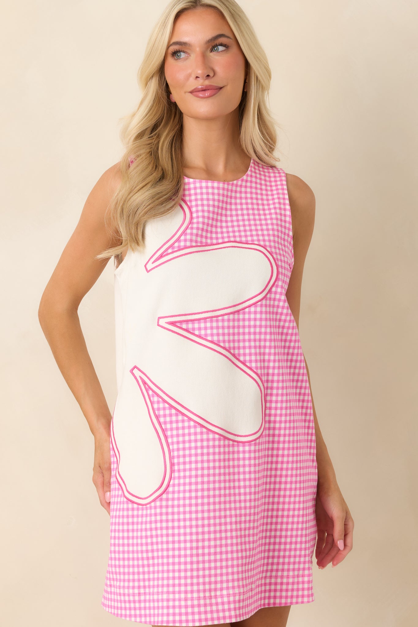 This gingham mini dress features a sleeveless silhouette, round neckline, and easy shift fit.