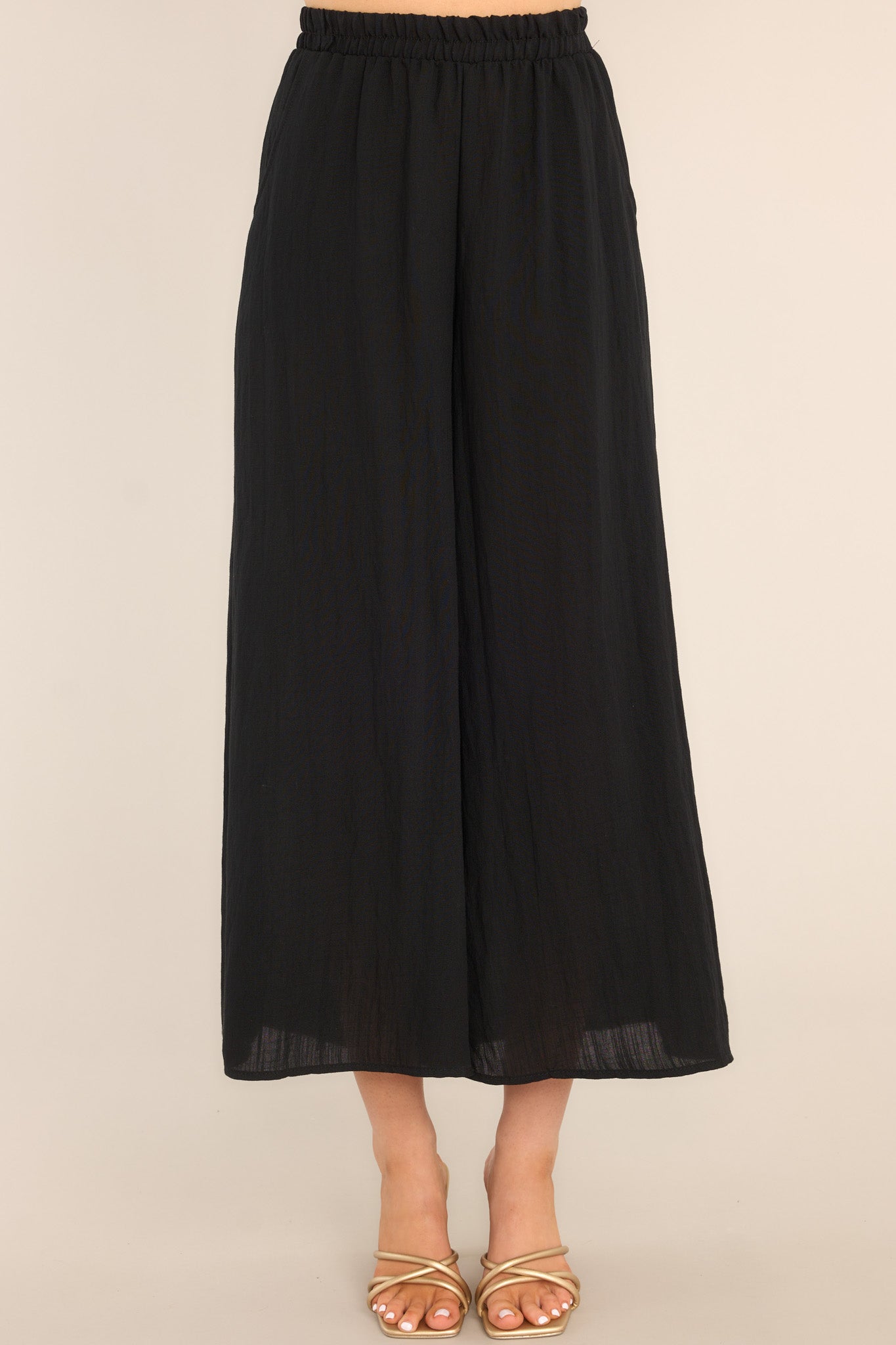 Front view of these pants that feature an elastic waistband, functional pockets, a cropped length, and a lightweight fabric.