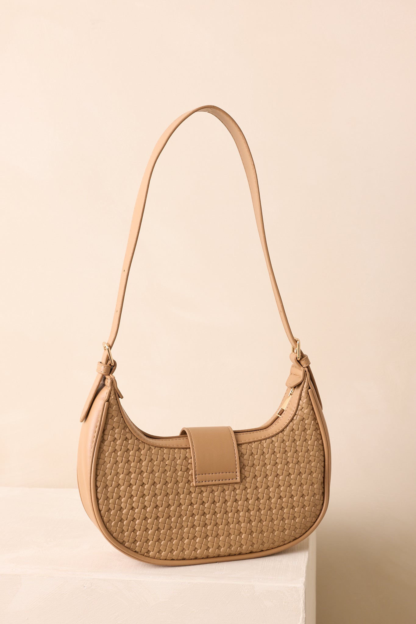 A back view of the handbag showing the smooth woven panel and curved half-moon shape.