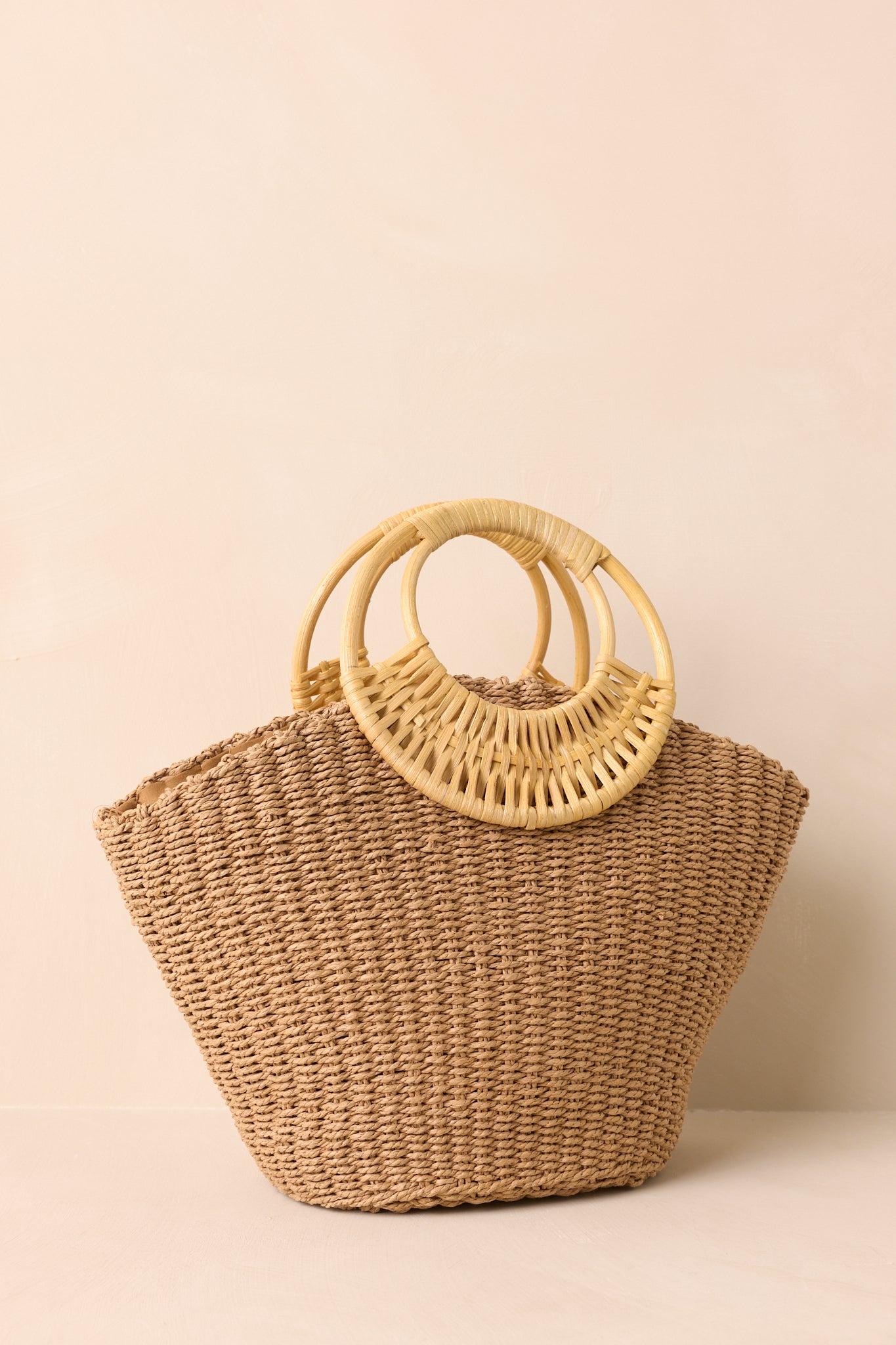 Tan raffia handbag highlighting bamboo handles and structured shape.
