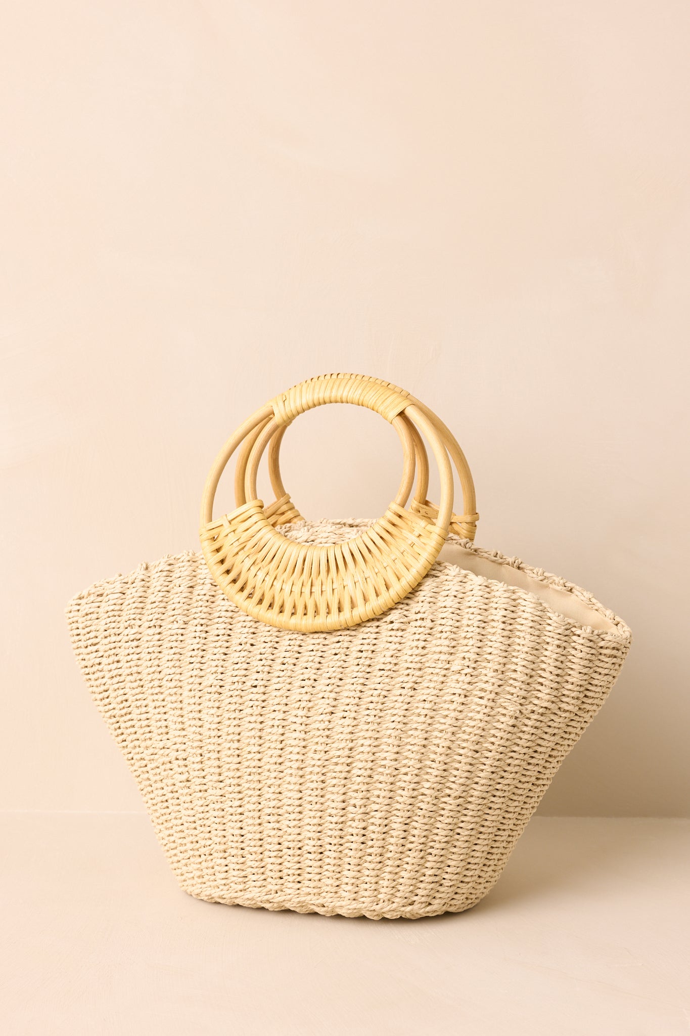 Close view of ivory raffia weave and smooth bamboo handles on handbag.