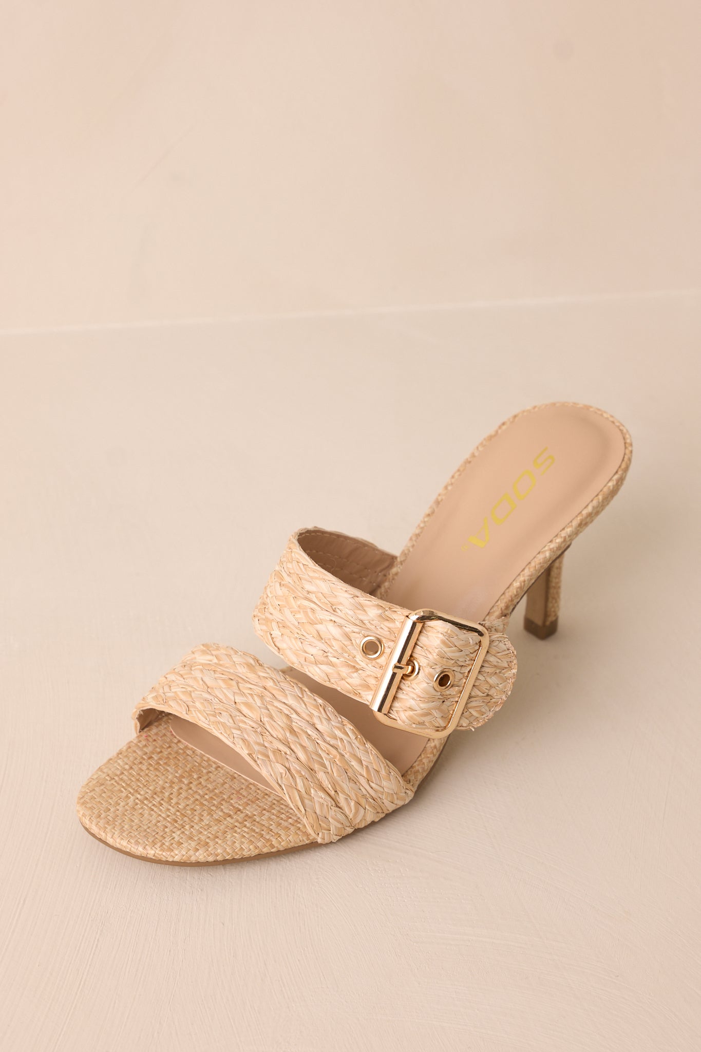A top-down view of the heels, focusing on the placement of the woven straps, gold buckle, and rounded toe shape.