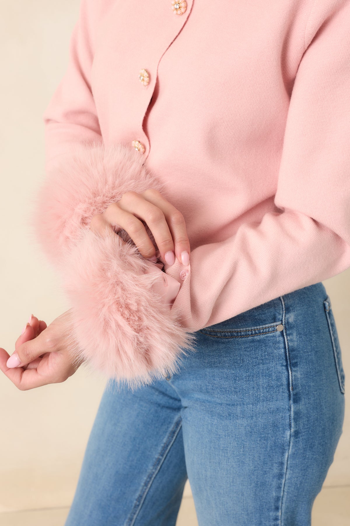 Close up of the removable fur cuff on a pink cardigan.