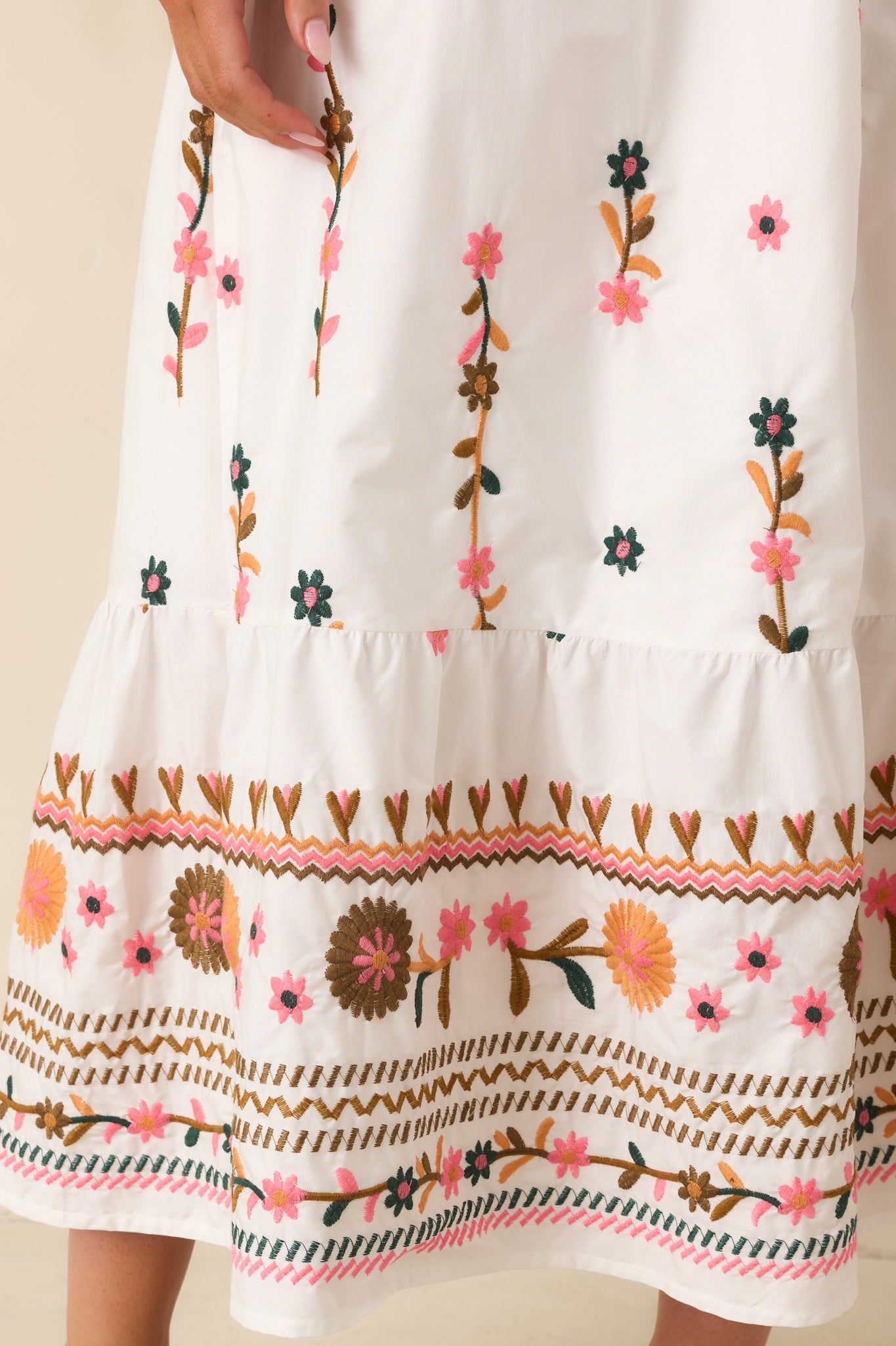 Close-up of ivory maxi dress highlighting delicate floral embroidery, border hem detailing, and cotton blend texture.