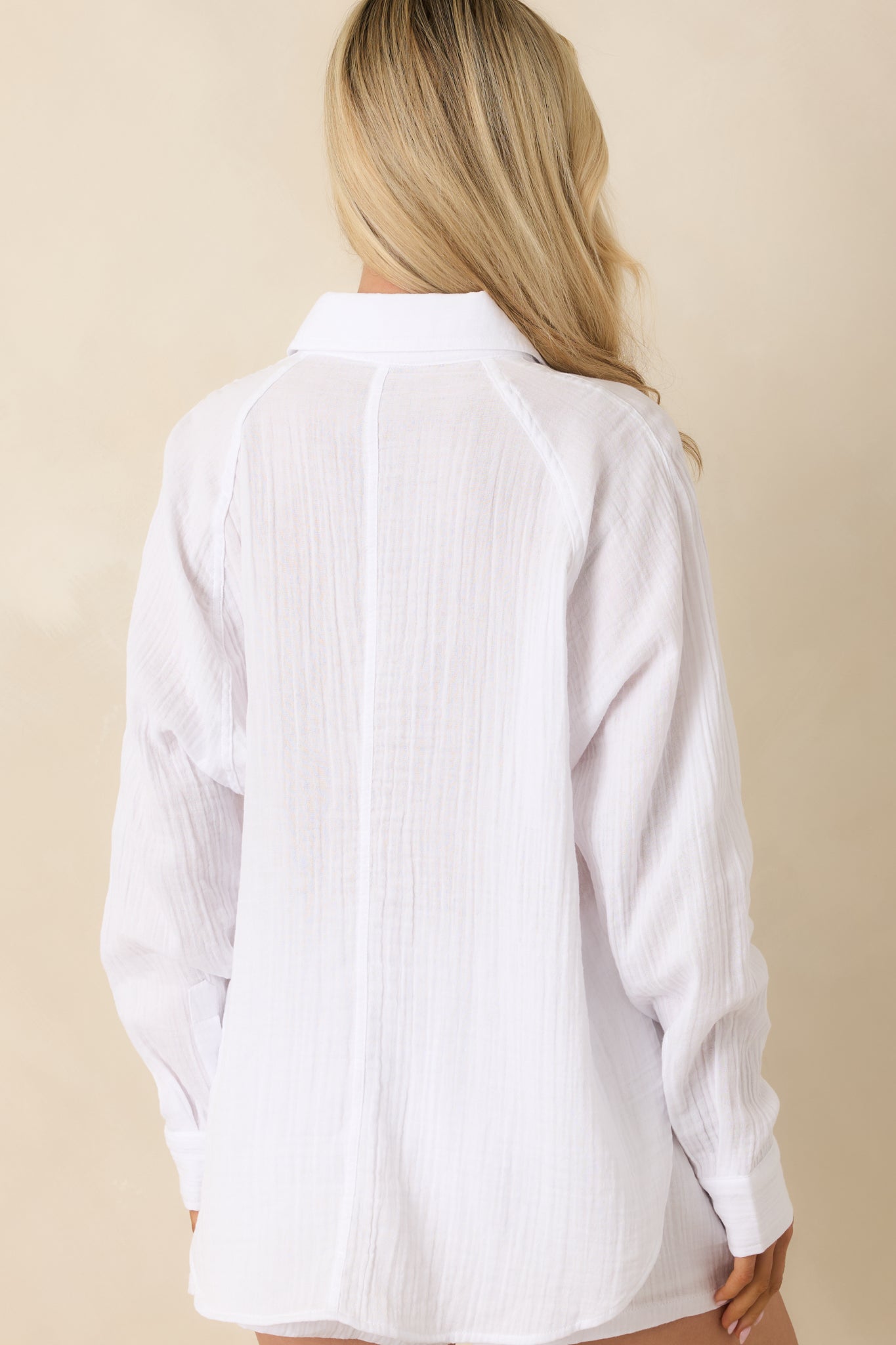 Back view of the white cotton gauze top featuring the relaxed oversized fit, long sleeves, and rounded hemline.