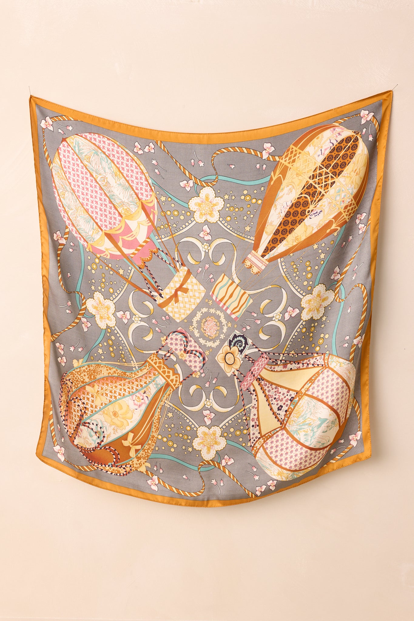 A complete view of the satin hair scarf featuring its slate gray base and all-over hot air balloon print.