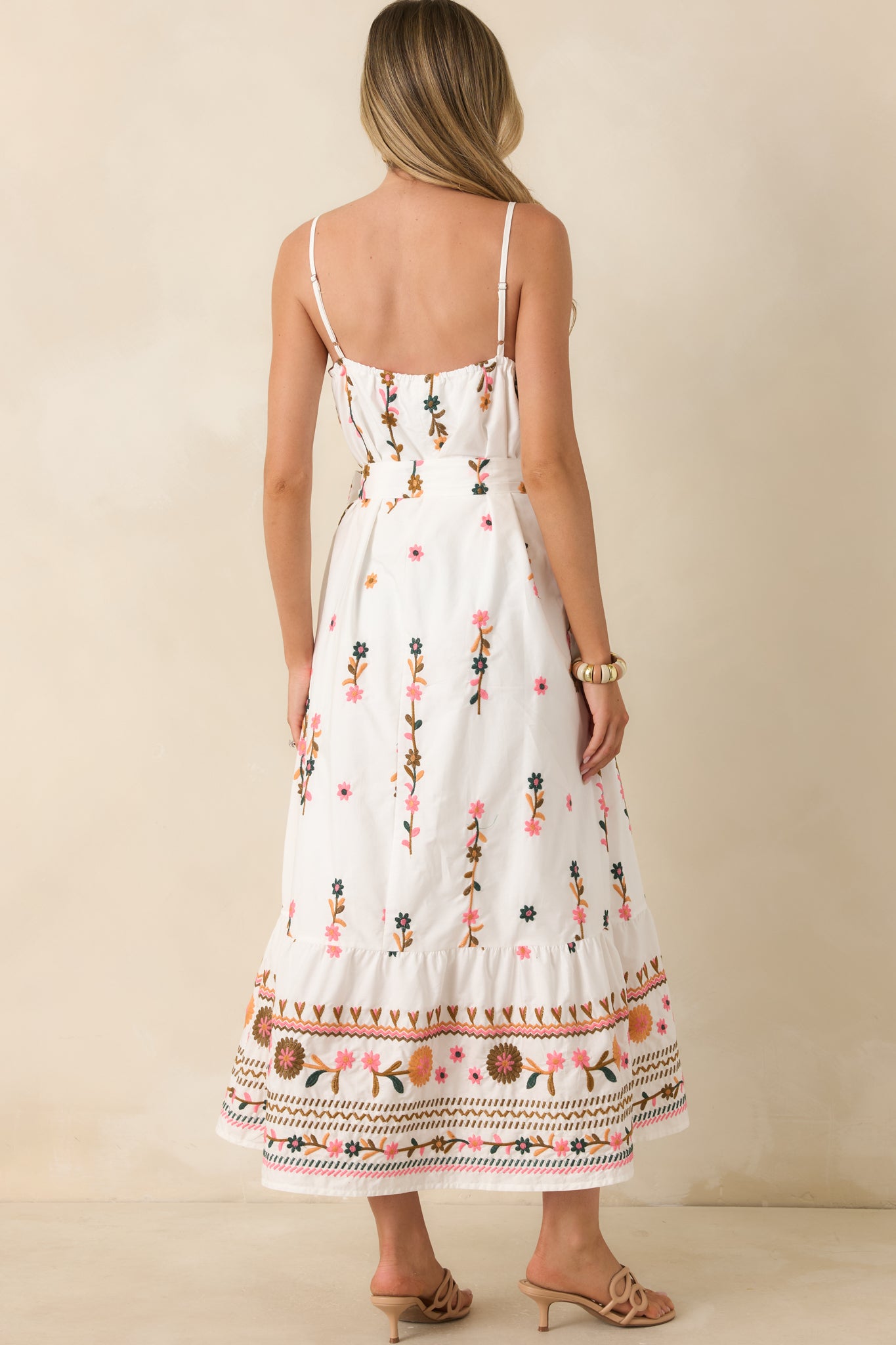 Rear view of ivory floral maxi dress showcasing adjustable spaghetti straps, gathered neckline detail, and flowing lined skirt.