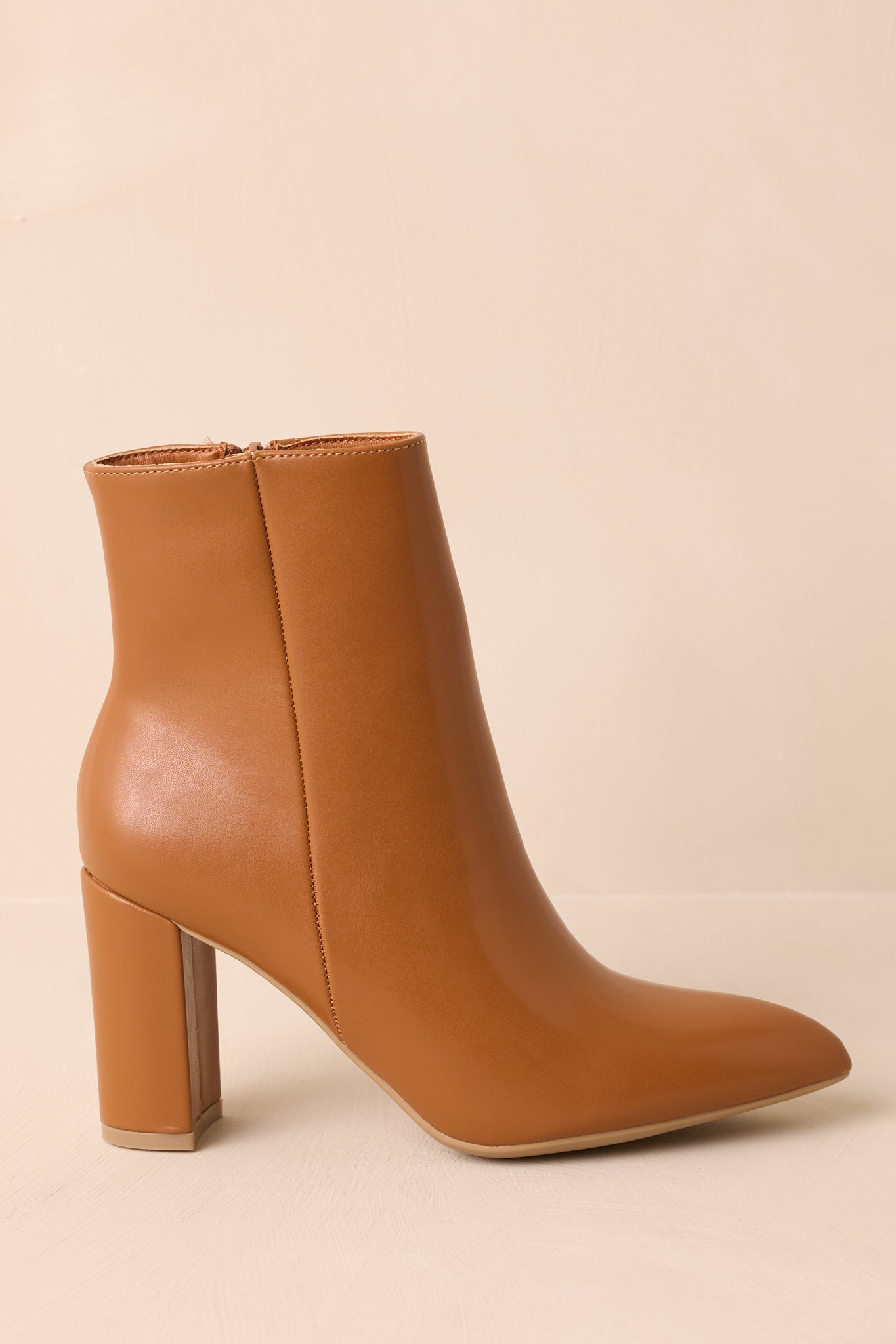 A close-up detail of the faux leather texture and stitching on the caramel brown ankle boots.
