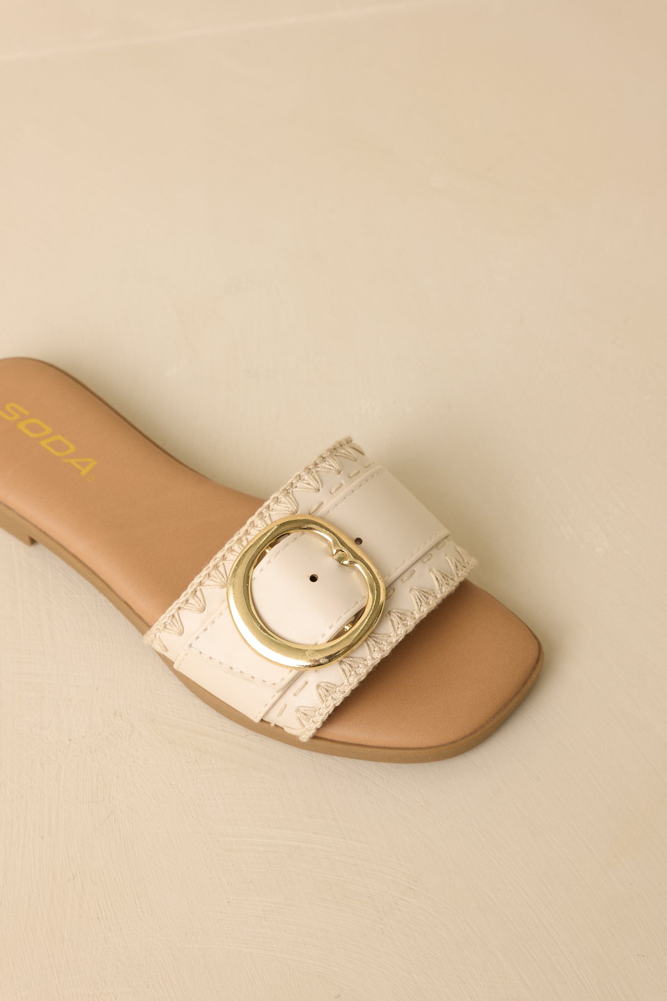 Close view of the gold-tone buckle and wide strap with smooth faux leather texture.