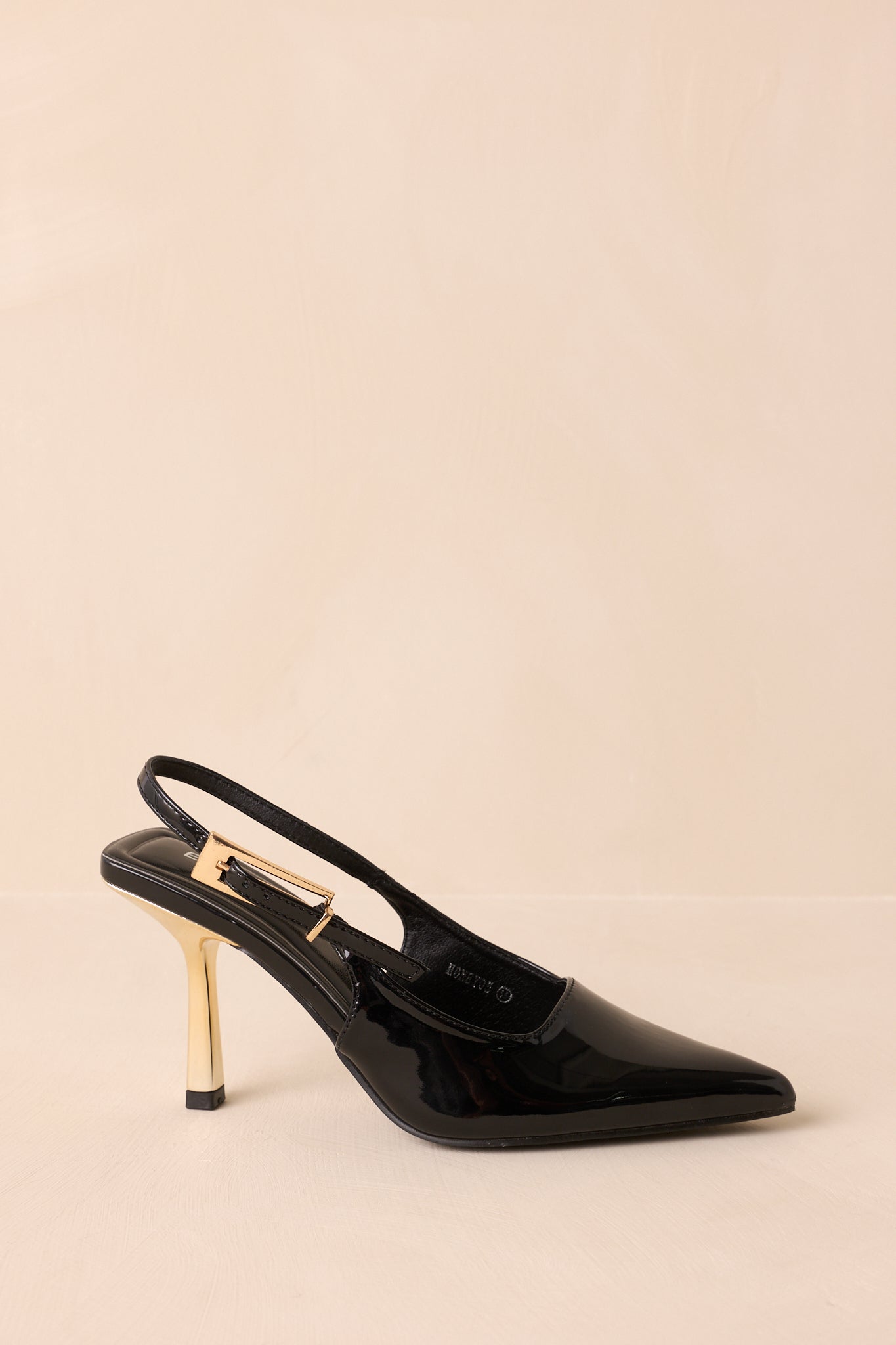 Side view of shiny black heels featuring adjustable slingback strap and gold buckle.