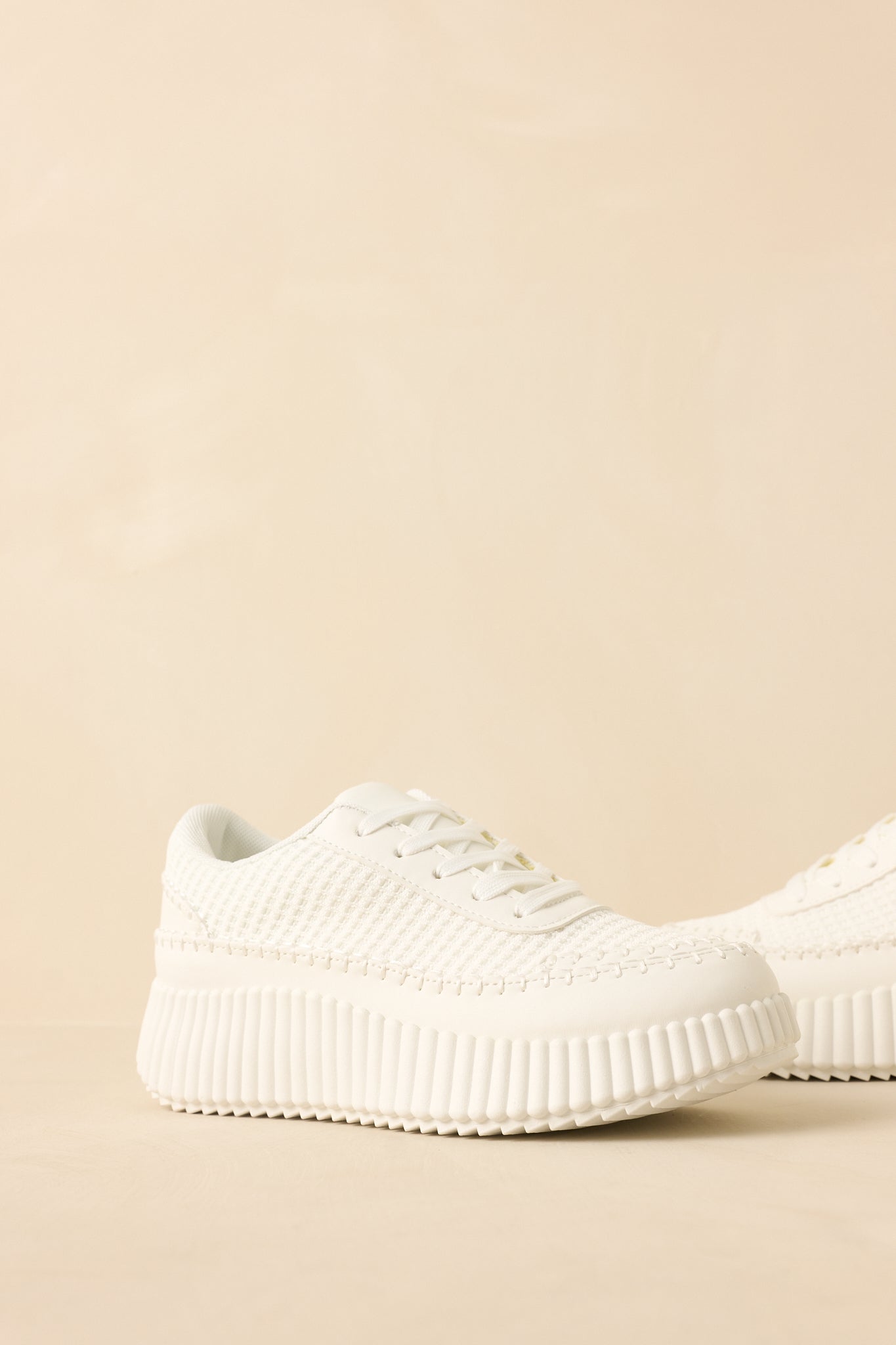 White knit sneakers showing the textured upper, lace-up front, and chunky ribbed platform sole.