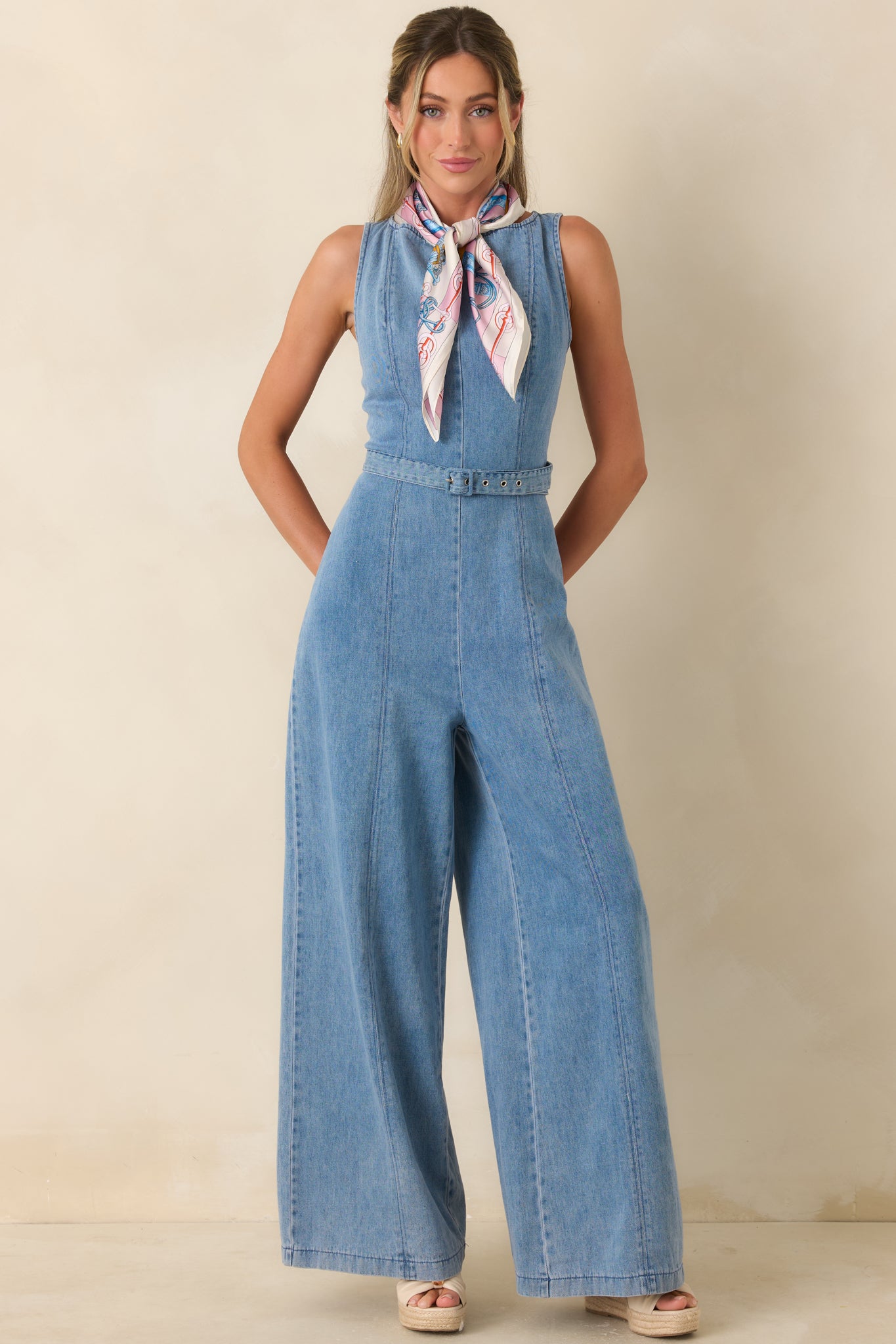 Denim jumpsuit with a high neckline, tailored waistline, and elongating seam detailing throughout.