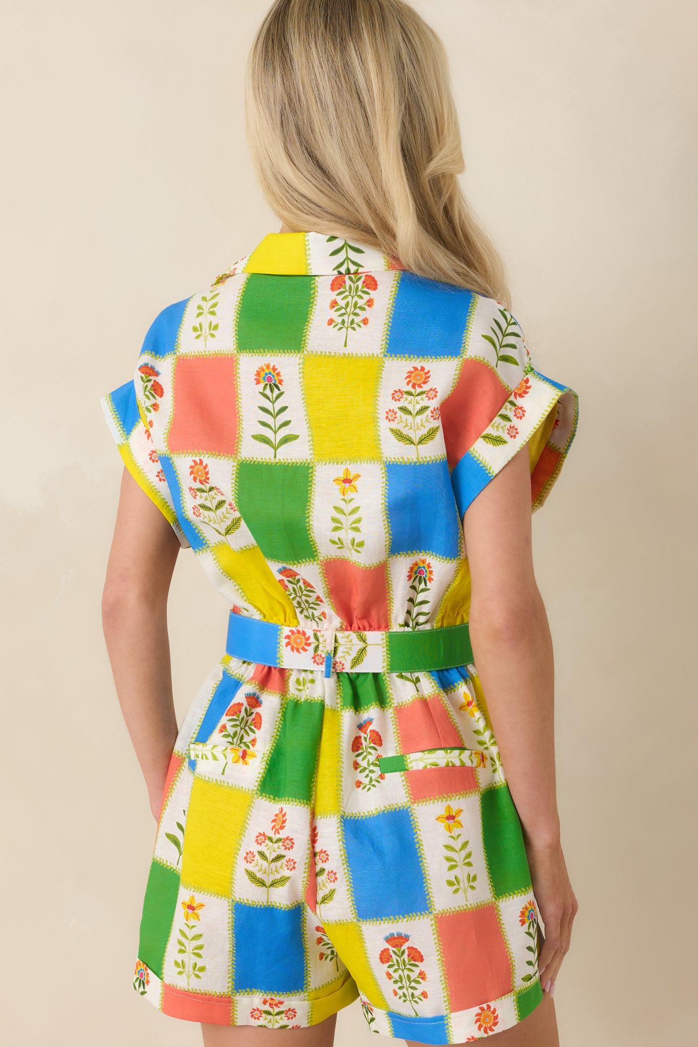 Rear view of the romper showing the continuous patchwork floral design, relaxed short sleeve fit, and gently structured silhouette flowing through the back.