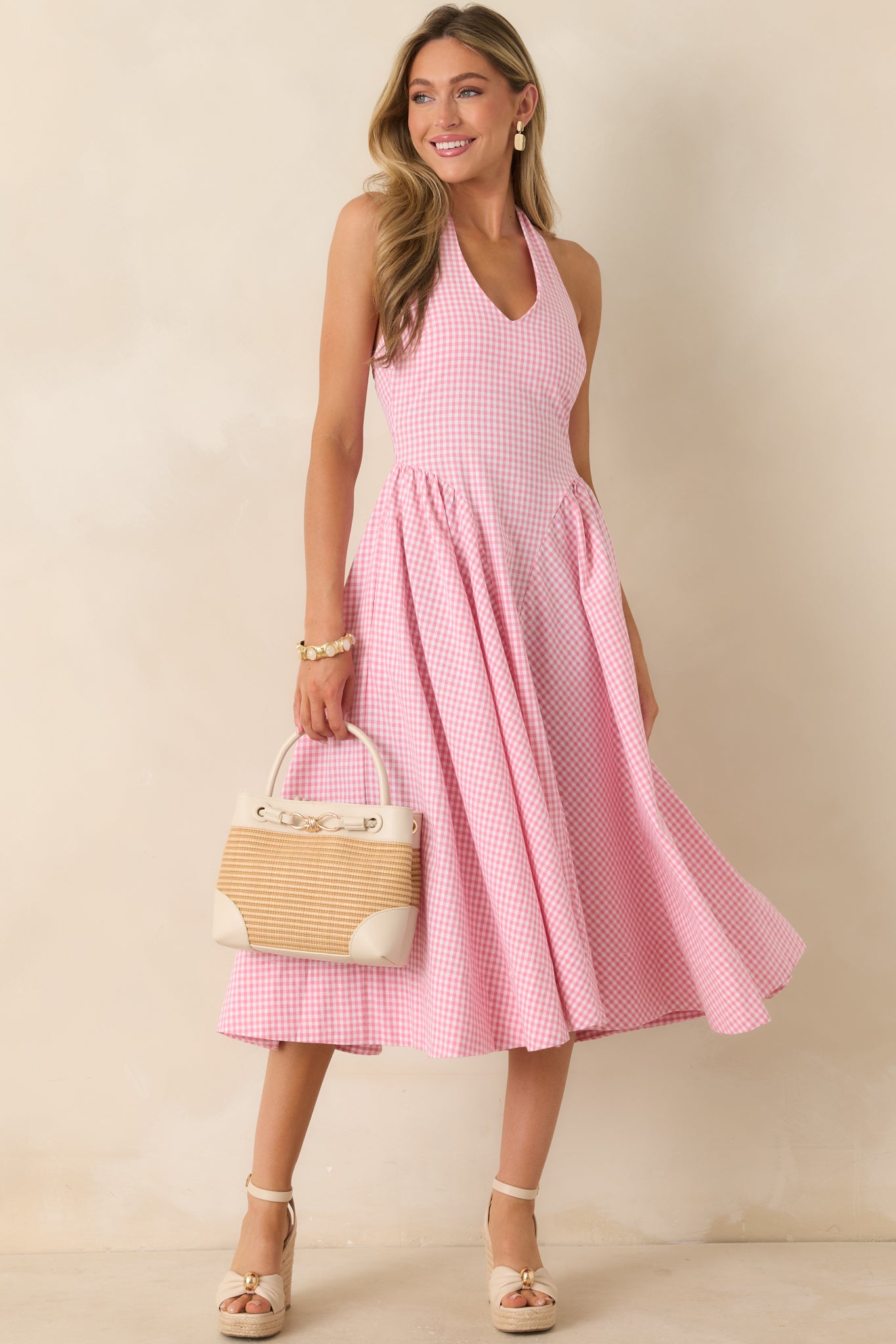 Pink checked cotton dress featuring a structured bodice, classic gingham print, and flowing gathered skirt design.