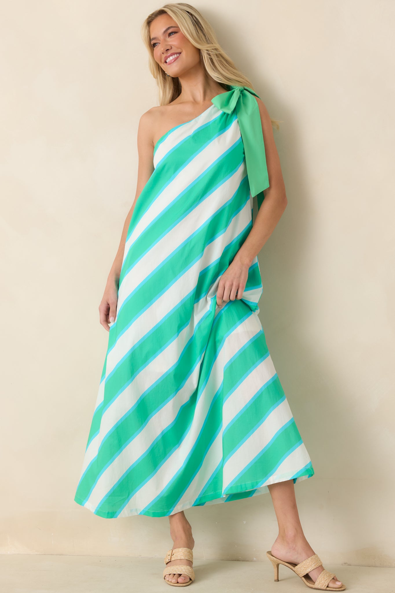 One-shoulder striped maxi dress showcasing a graceful draped shape, side pockets, and fluid movement throughout the skirt.